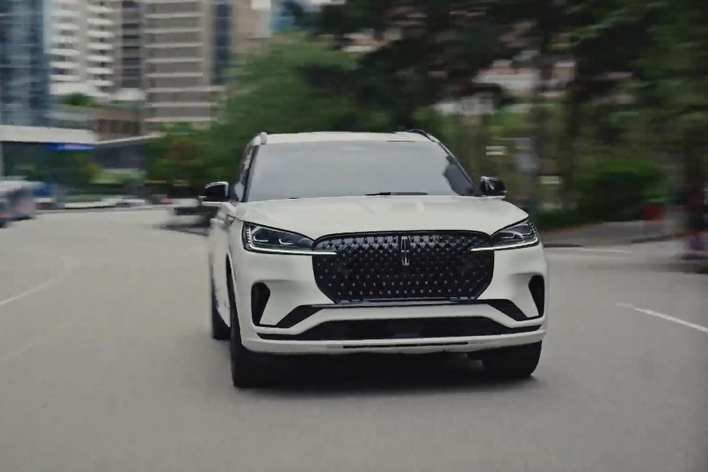 A 2026 Lincoln Aviator® SUV is being driven on a highway near a city