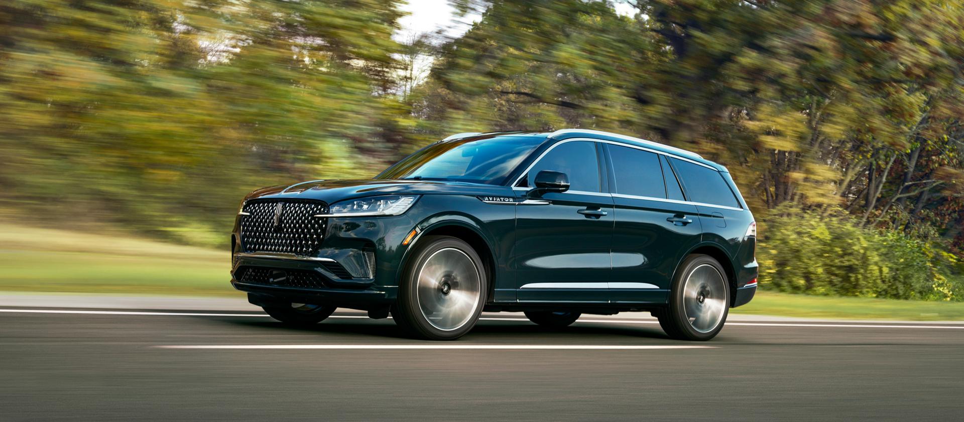 A 2027 Lincoln Aviator® Black Label™ SUV is being driven in a lush countryside