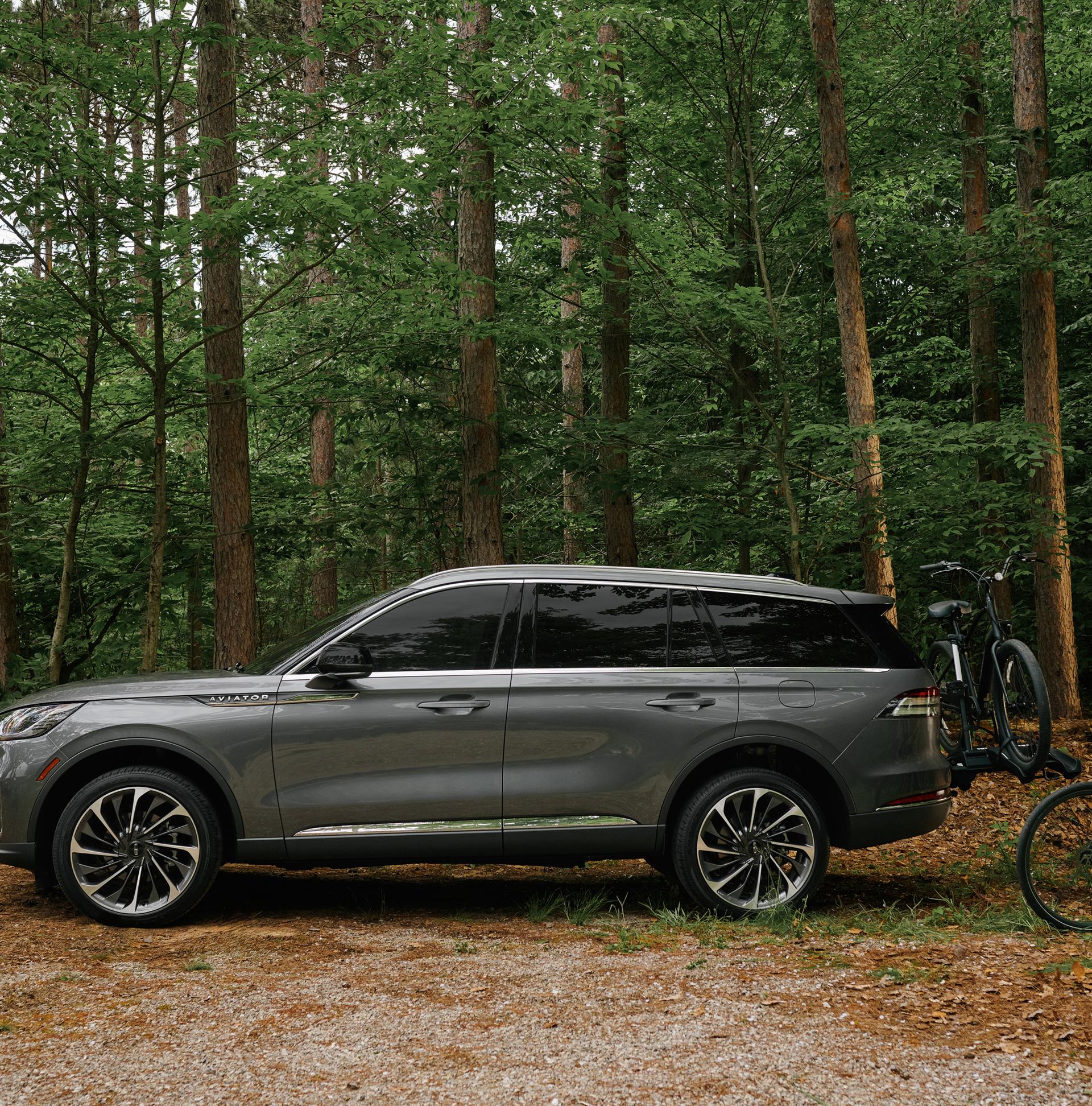 A father and son load bicycles onto a bike rack attached to a 2027 Lincoln Aviator® SUV