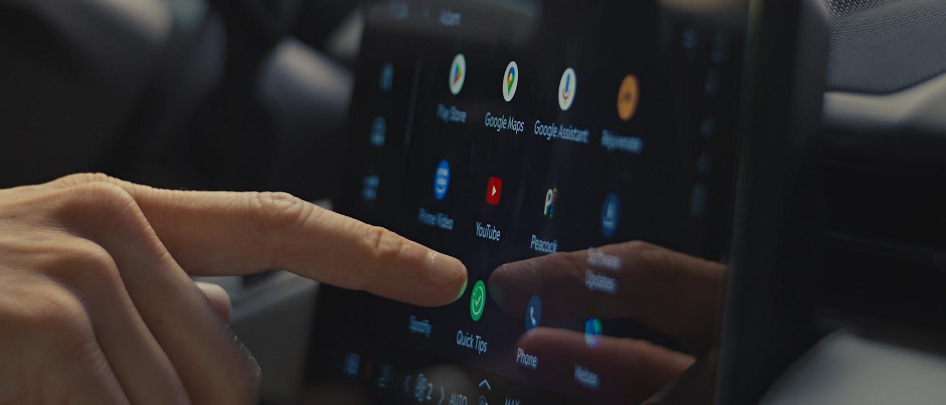 A person uses the center touch screen to receive driving tips