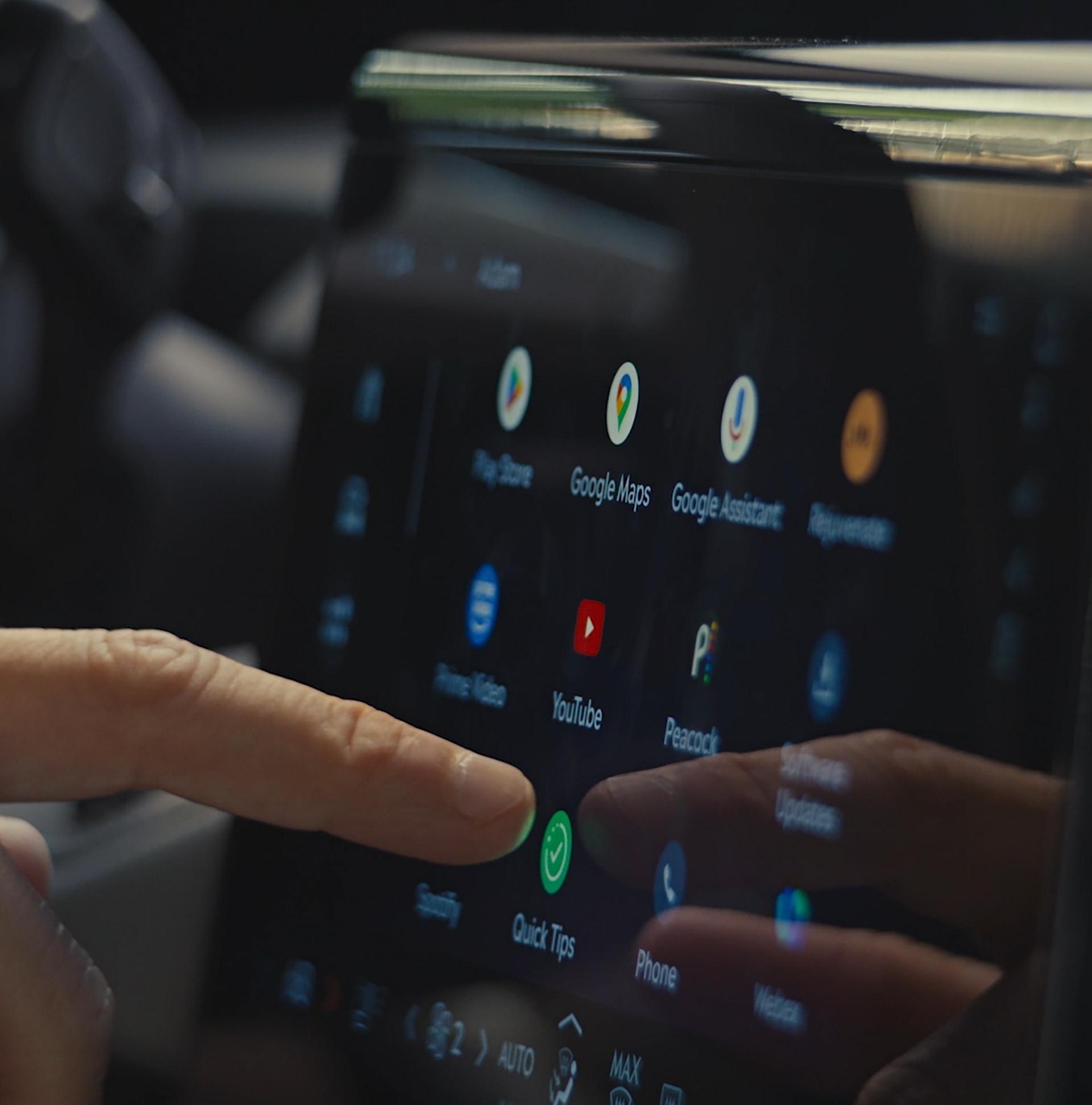 A person uses the center touch screen to receive driving tips