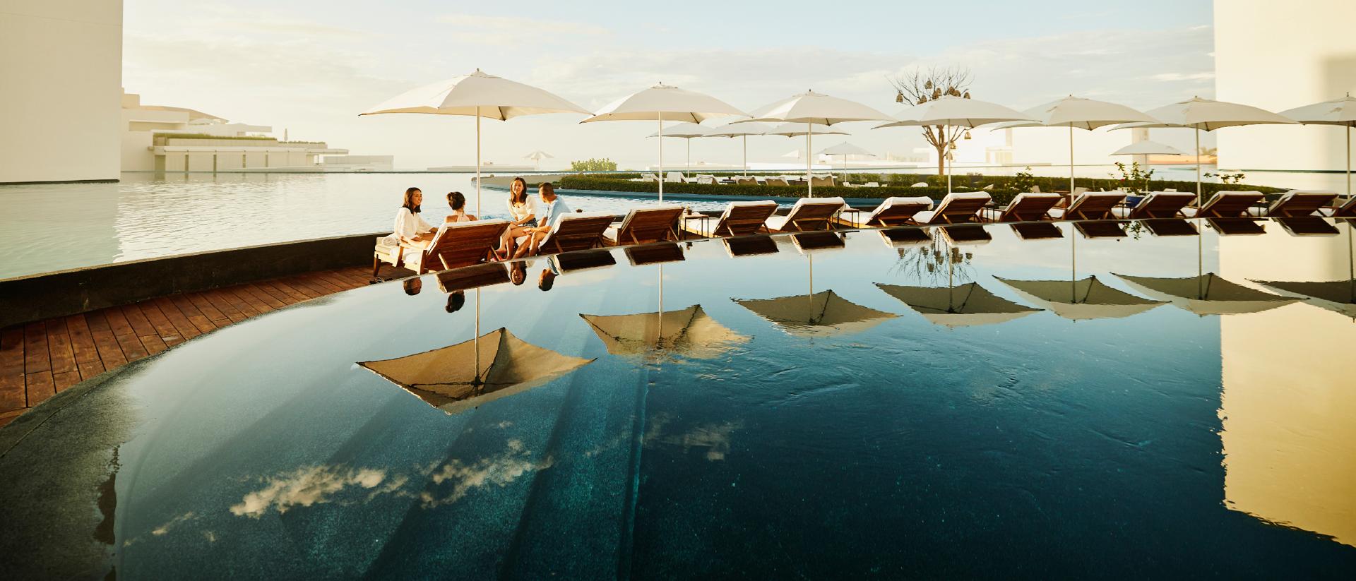 A group of people sitting poolside and chatting.