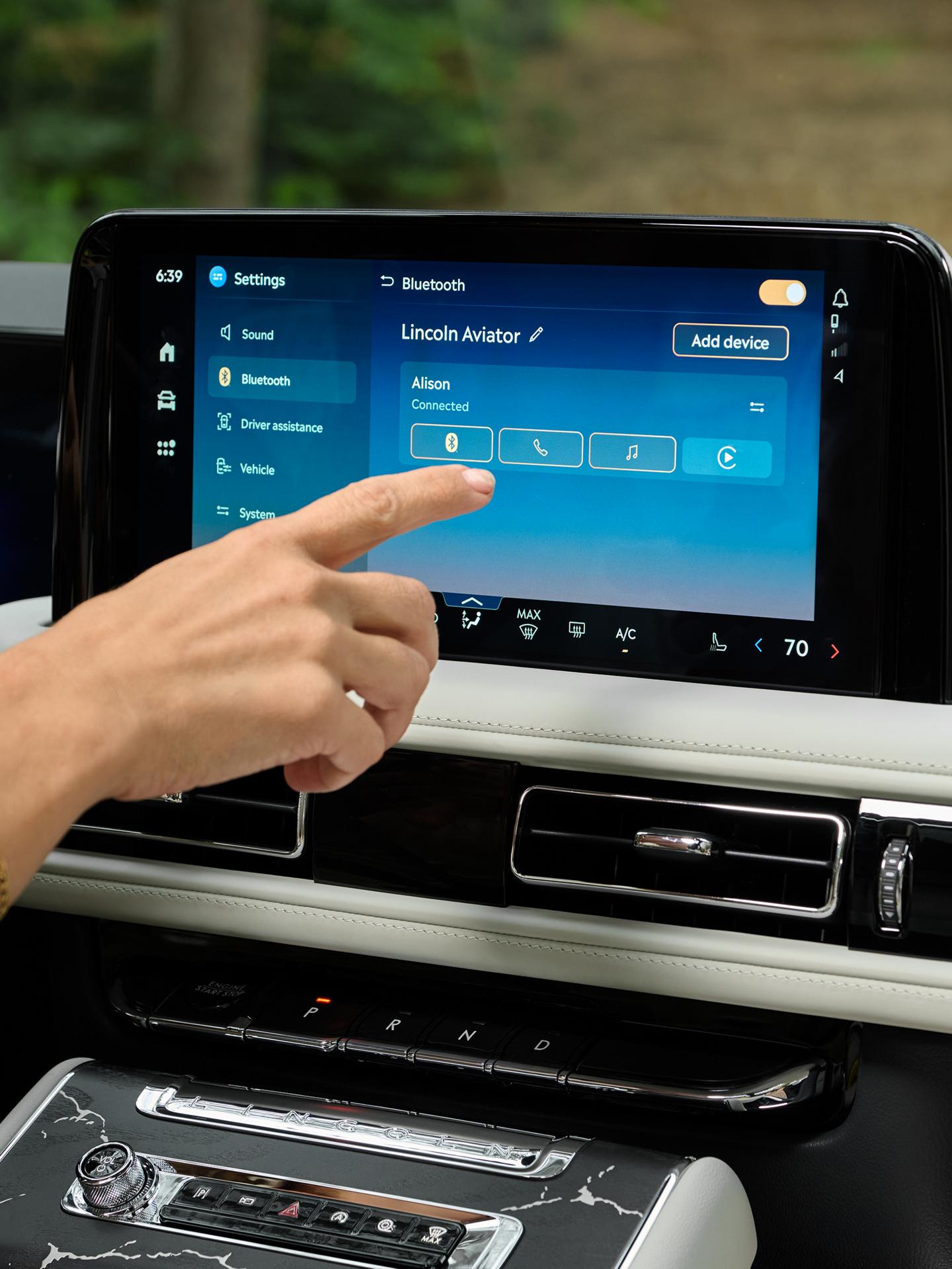 A hand reaches out to interact with the center touchscreen of a 2027 Lincoln Aviator® SUV