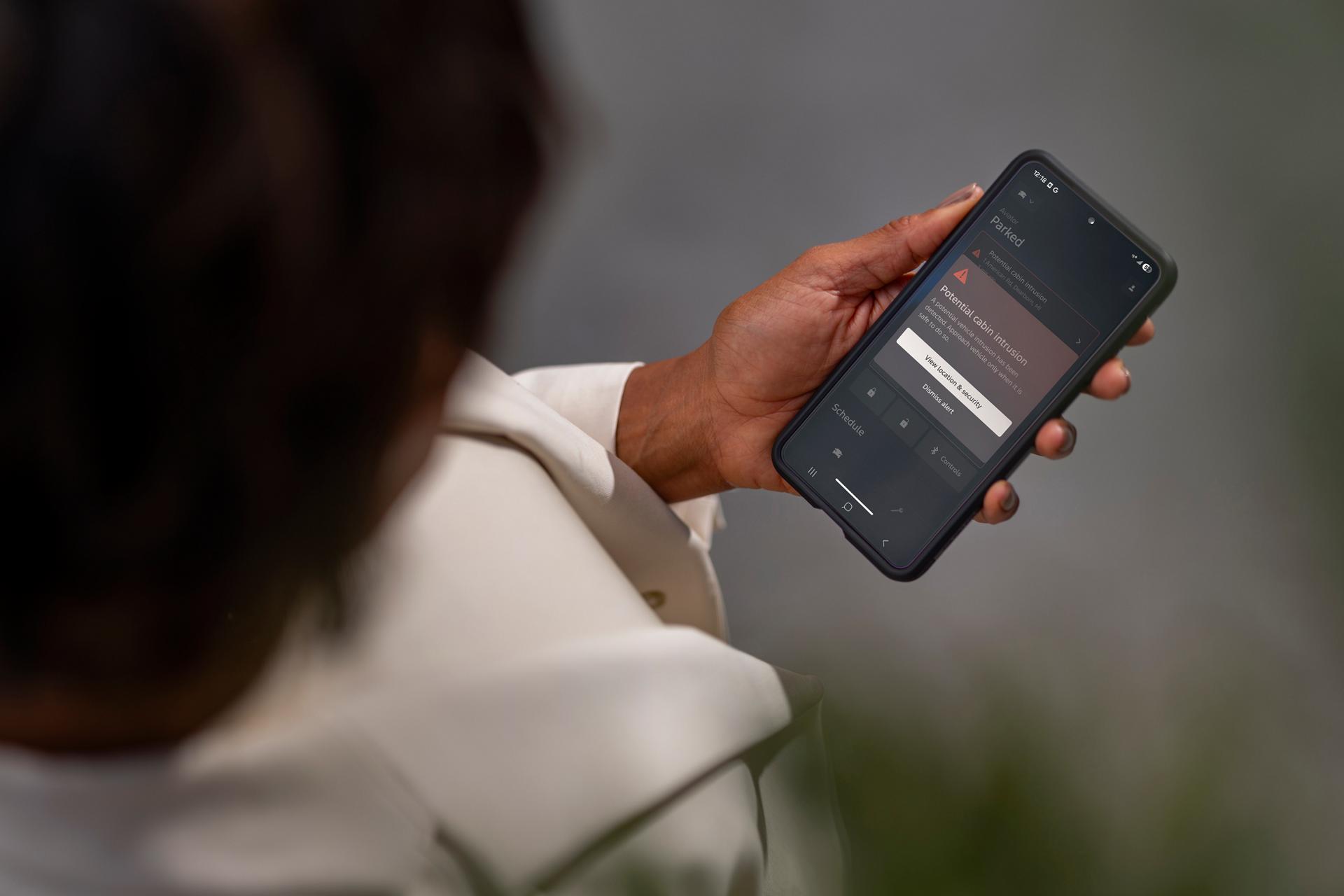 A woman uses her mobile phone to check the security status of her vehicle