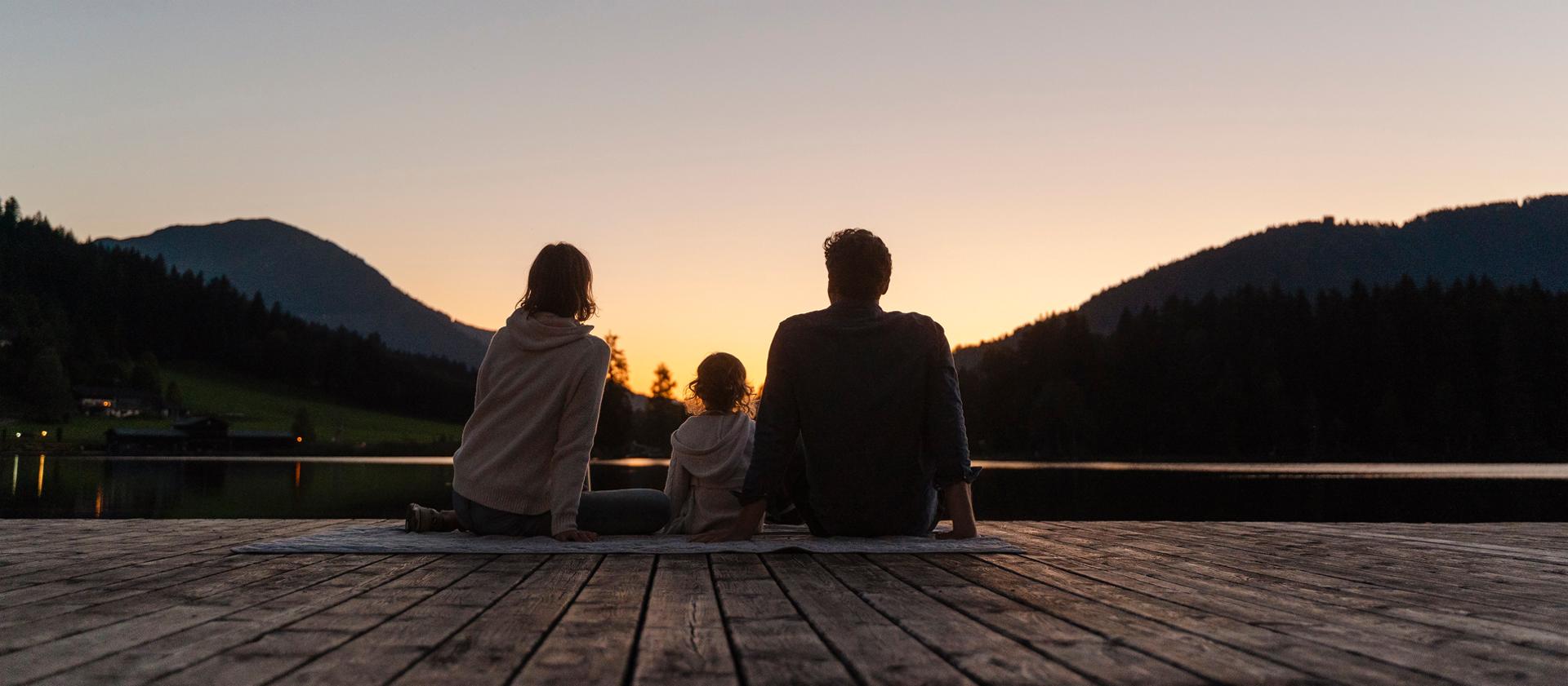 A family sits outdoors at sunset in anticipation of the rising moon