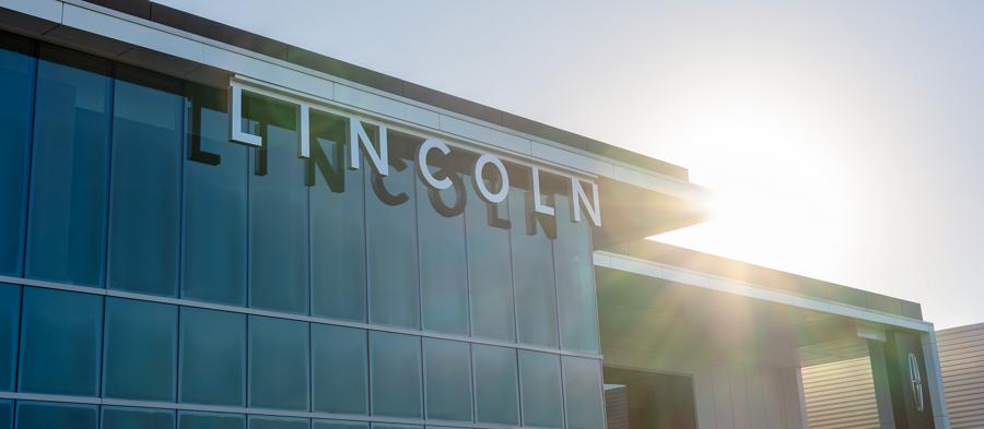 Lincoln dealership building on a clear morning with sunlight.