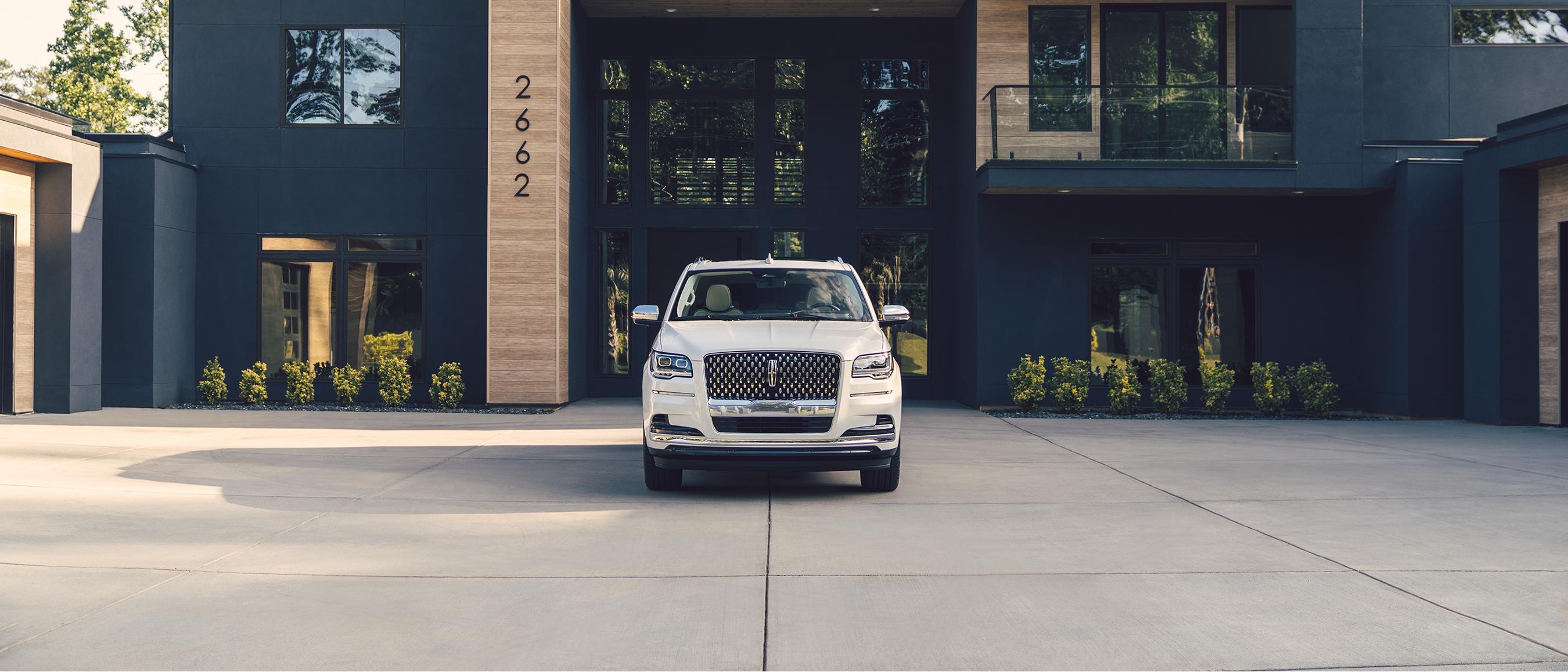 A Lincoln Navigator® SUV is parked in front of a modern home with black siding and wood accents