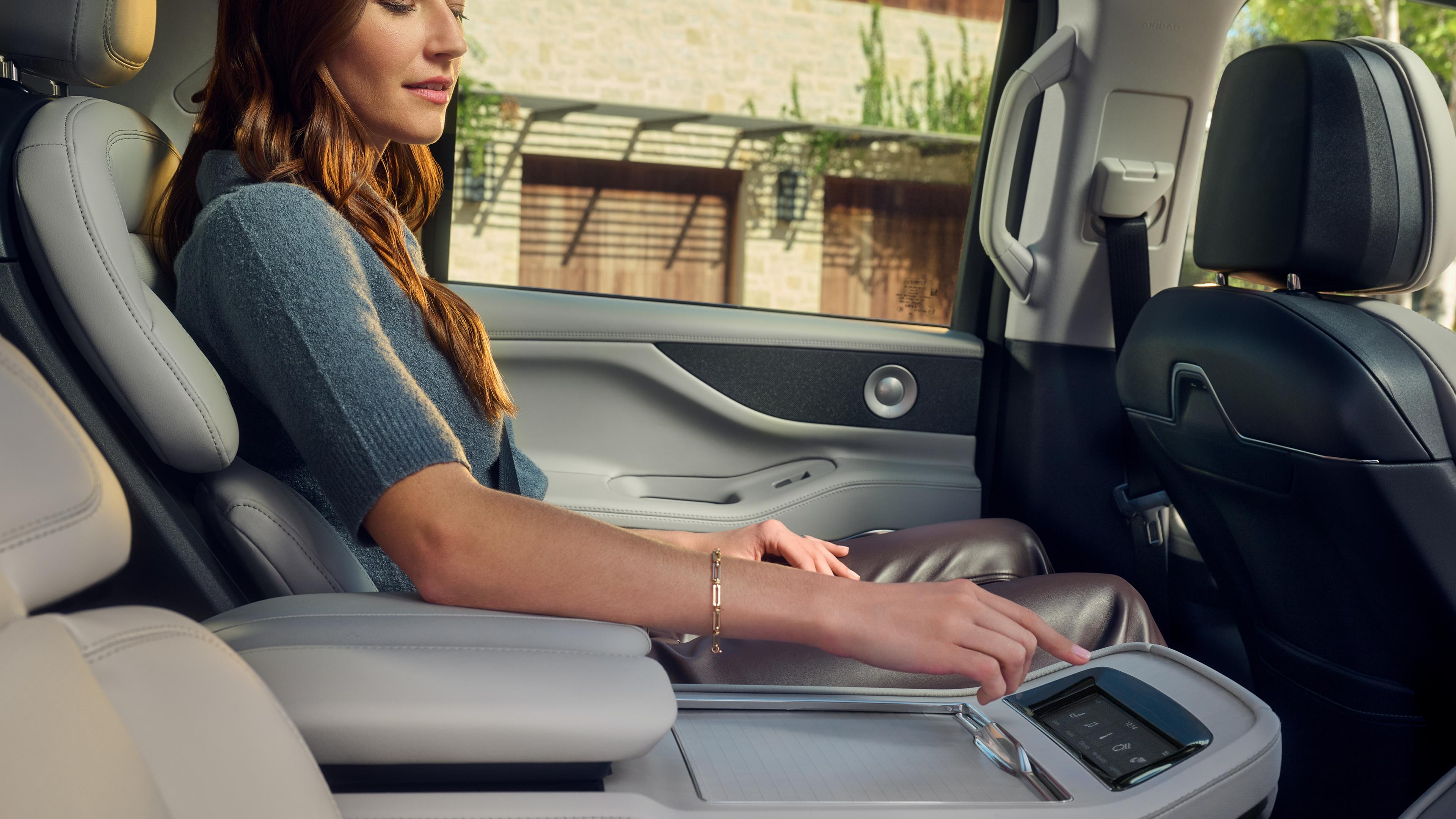 A woman in the second row of a Lincoln Navigator Reserve uses the center console control screen