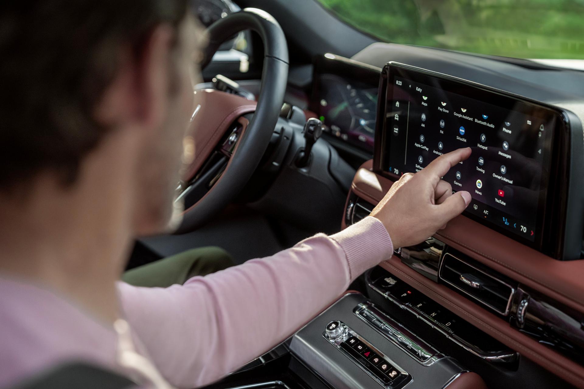 The front passenger of a 2027 Lincoln Aviator® SUV interacts with the center touchscreen