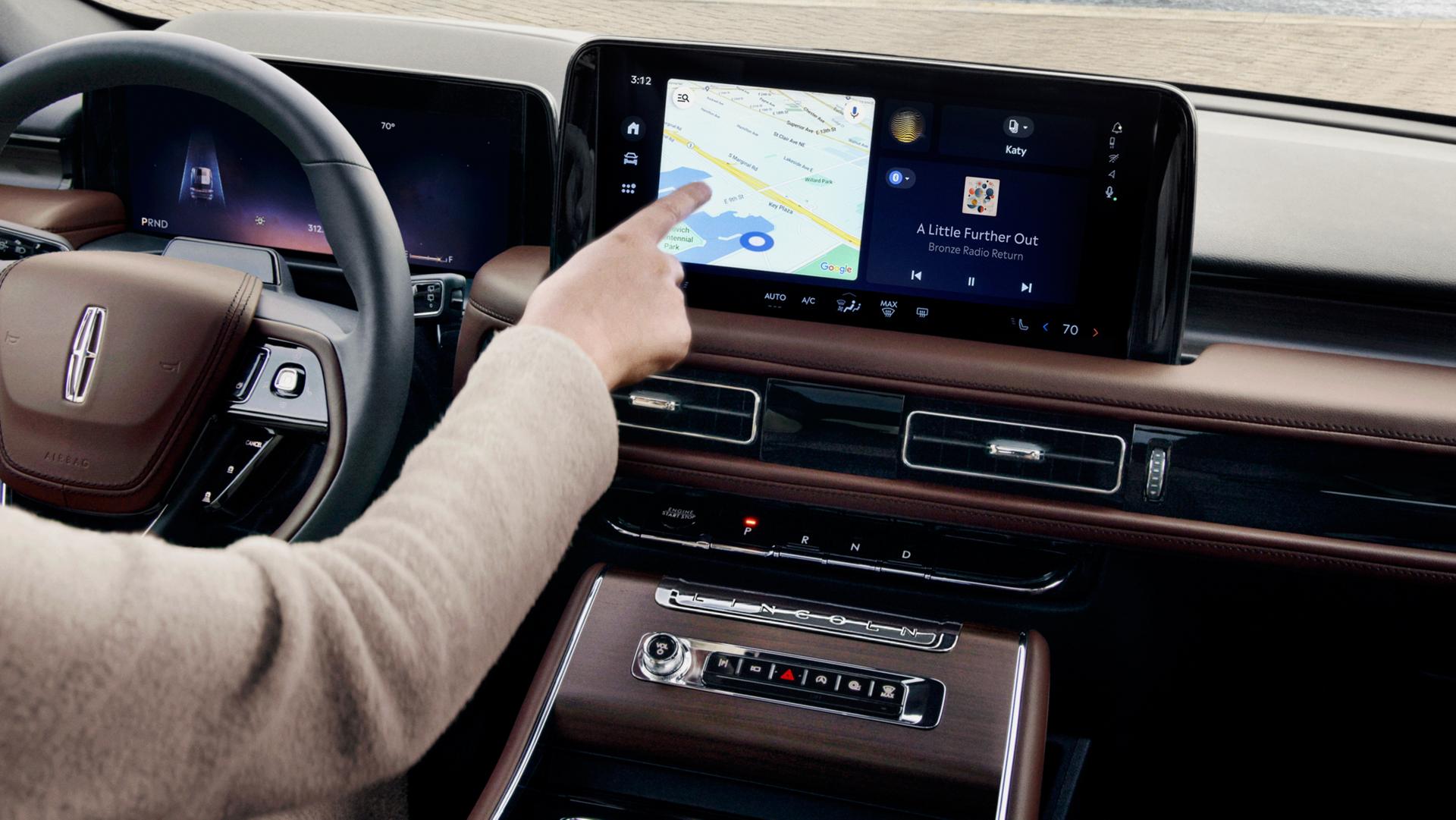 The driver of a 2027 Lincoln Aviator® SUV interacts with a map on the center touchscreen