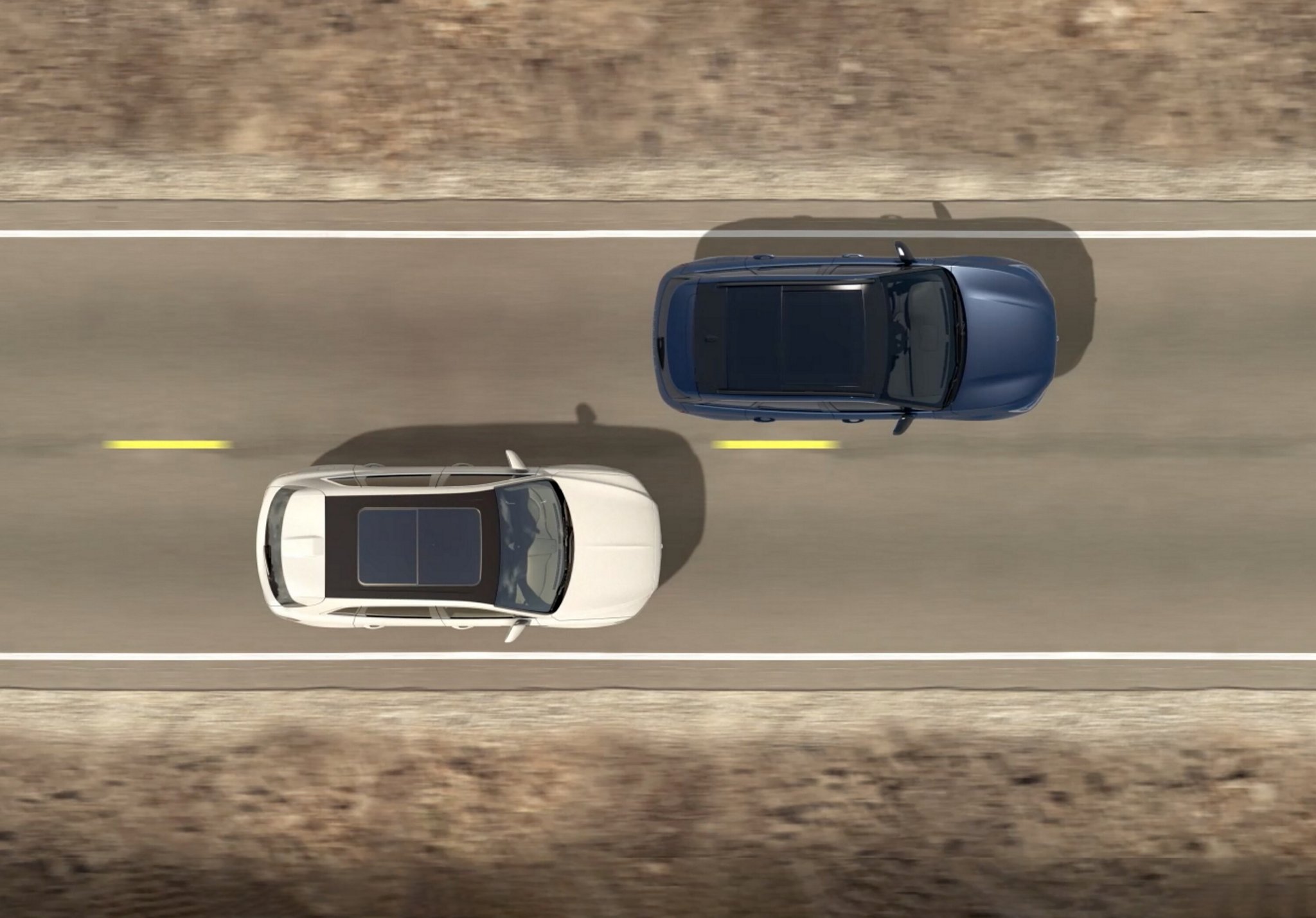 Two cars are seen from a birds eye view driving down a road.