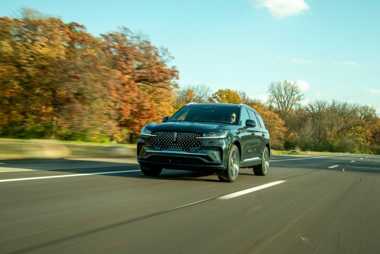 A 2026 Lincoln Aviator® SUV is shown driving on a tree-lined road