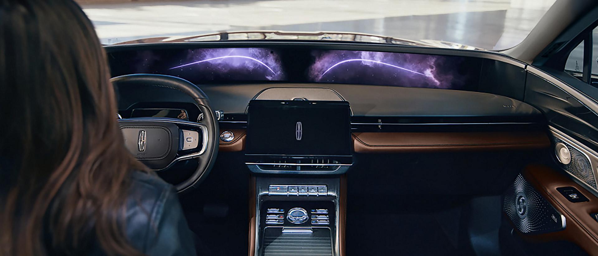 A person seated in the drivers seat of a 2026 Lincoln Nautilus® SUV touches the center screen