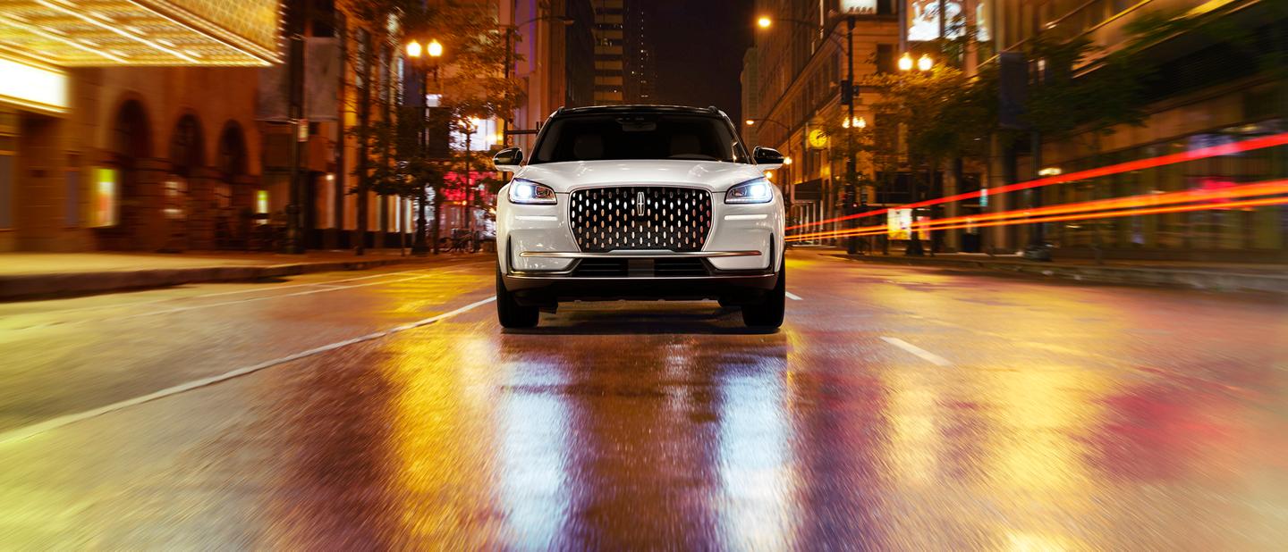 A Lincoln Corsair® SUV is parked on street with city lights reflecting off the wet pavement
