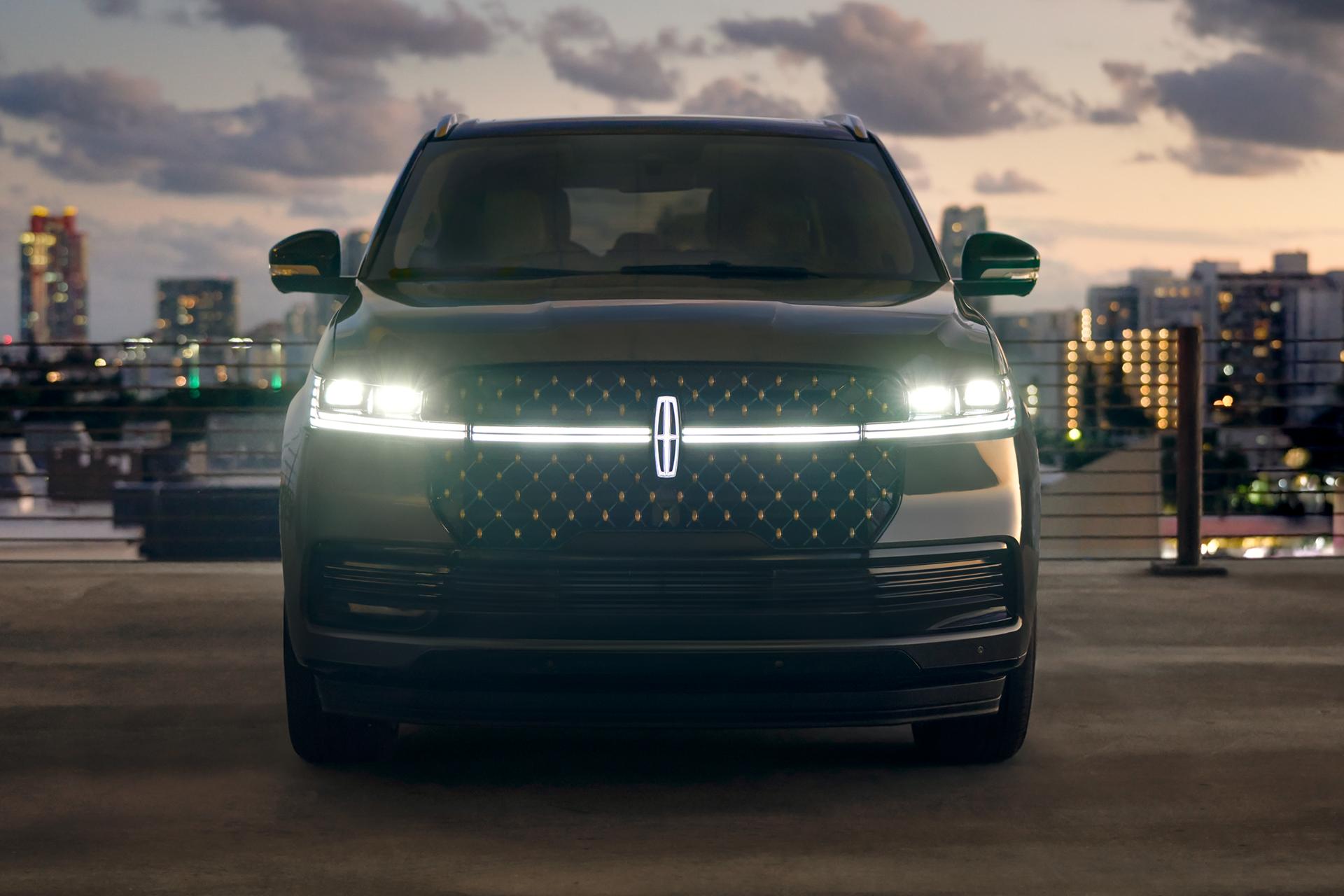The front of a 2027 Lincoln Navigator® SUV with headlamps and Lincoln Star illuminated at dusk