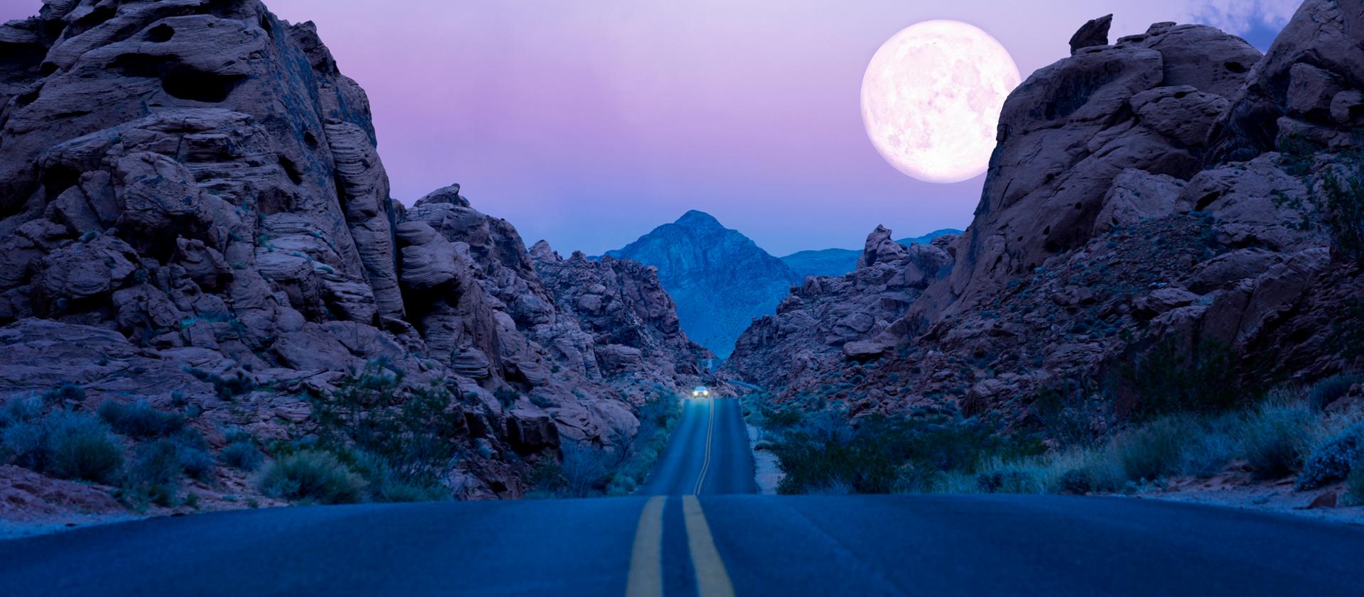 The moon rises above a desert southwest highway at night