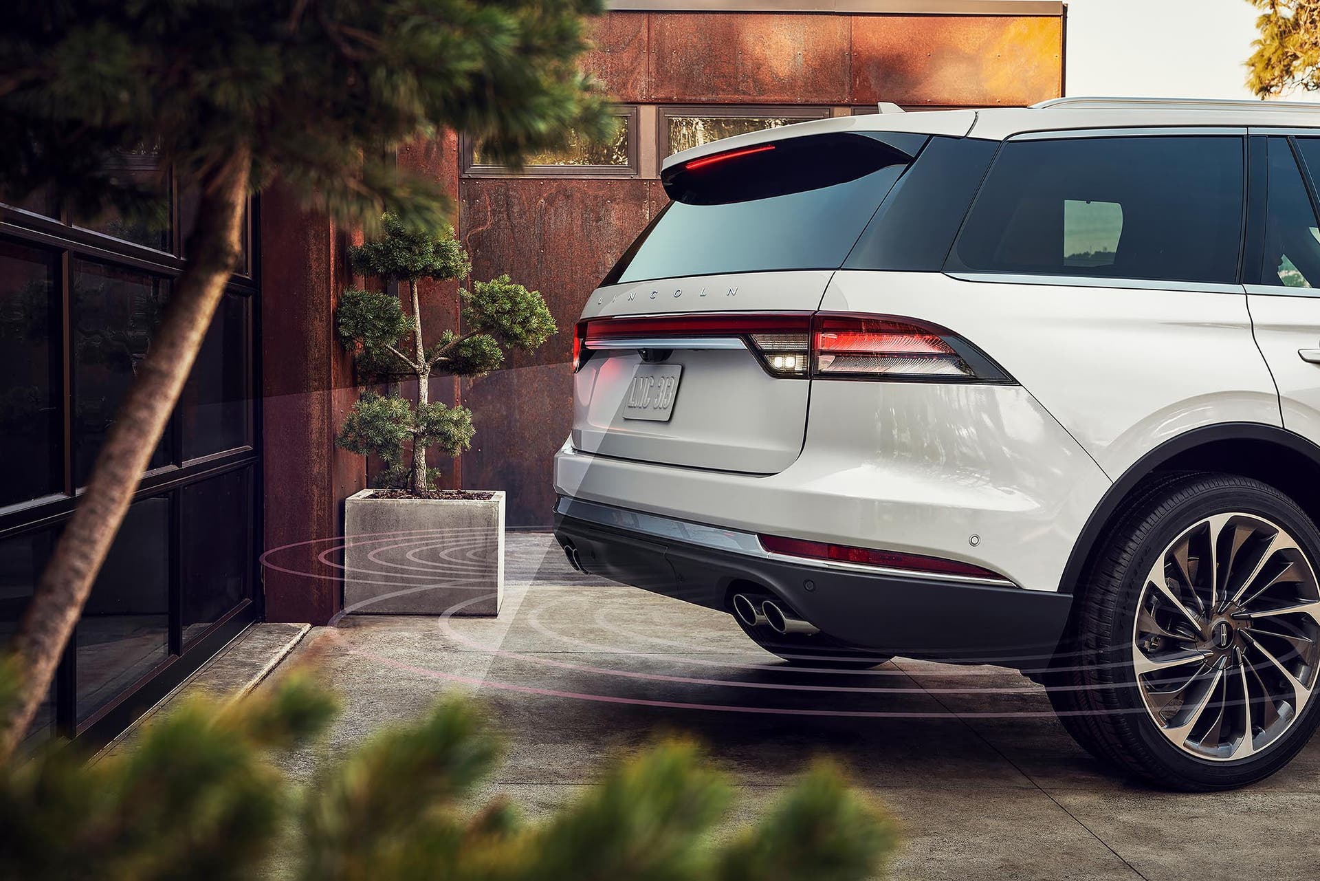 A 2027 Lincoln Aviator® SUV is reversing towards a garage with simulated radar beams