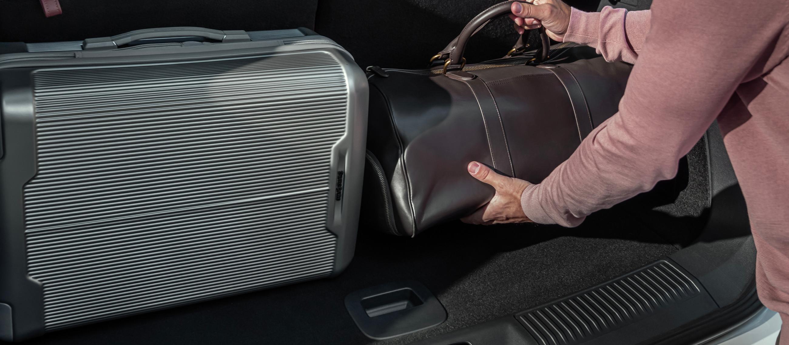 A person loads a leather bag into the rear cargo area of a 2026 Lincoln Aviator® SUV