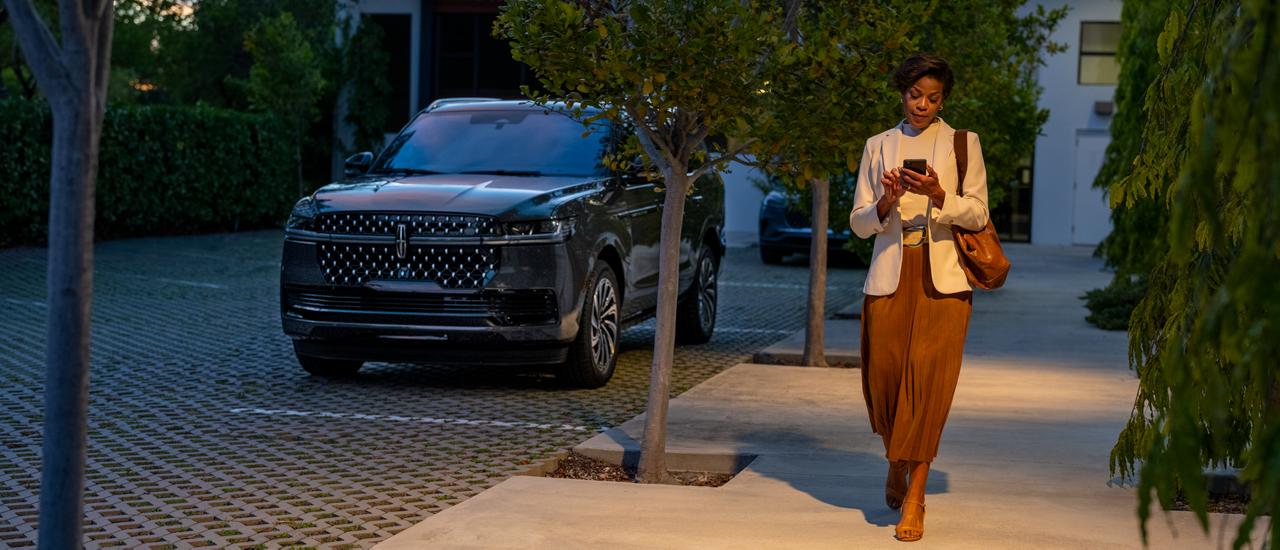 A woman walks away from her 2027 Lincoln Navigator® SUV at night