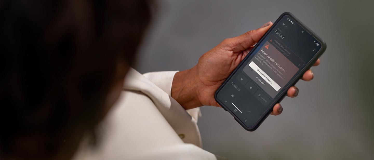 Person holding a smartphone displaying the Lincoln security app interface.