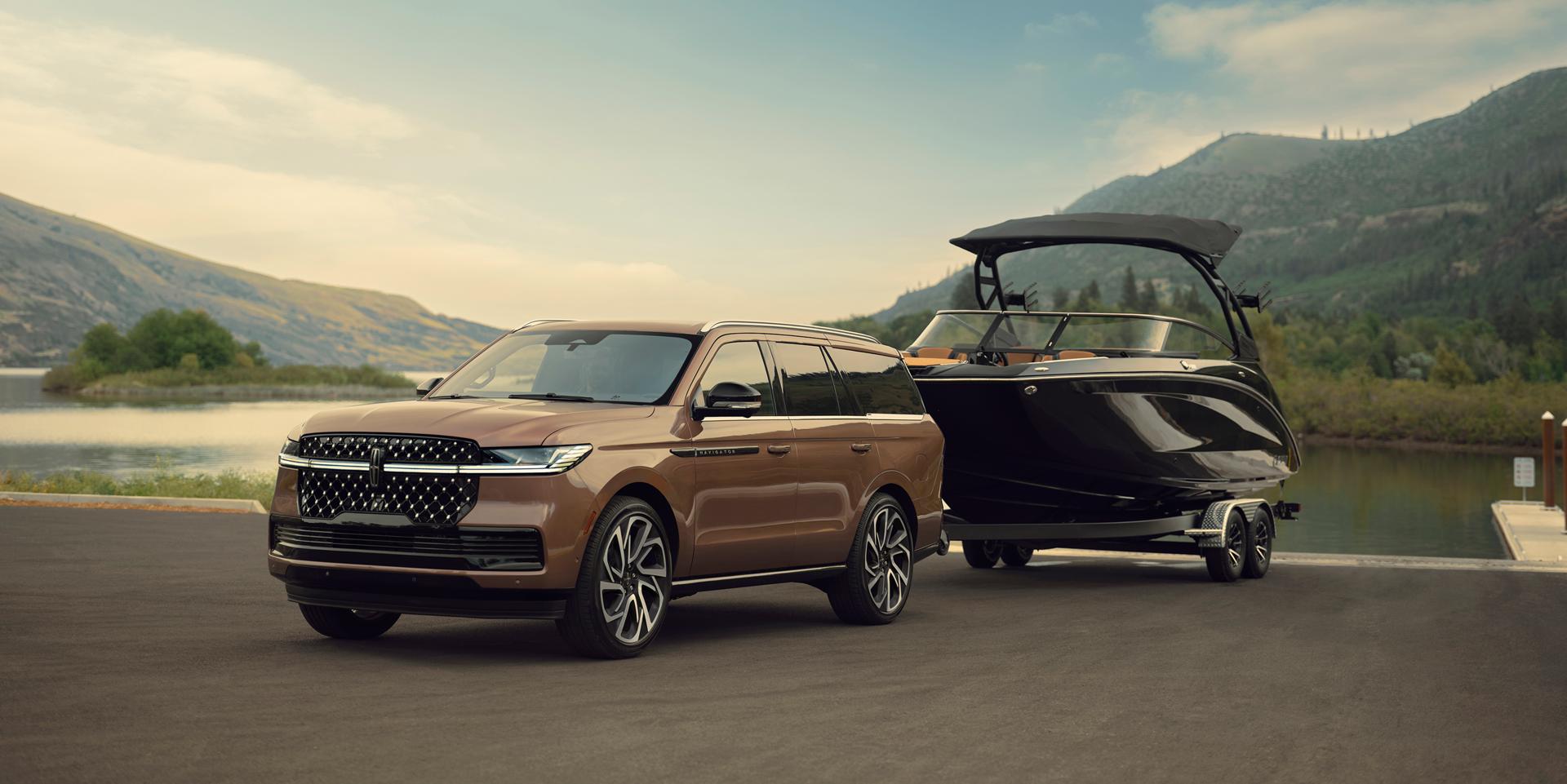 Un vehículo Lincoln Navigator® Black Label 2026 está estacionado frente a un pintoresco paseo marítimo con un bote de recreo enganchado