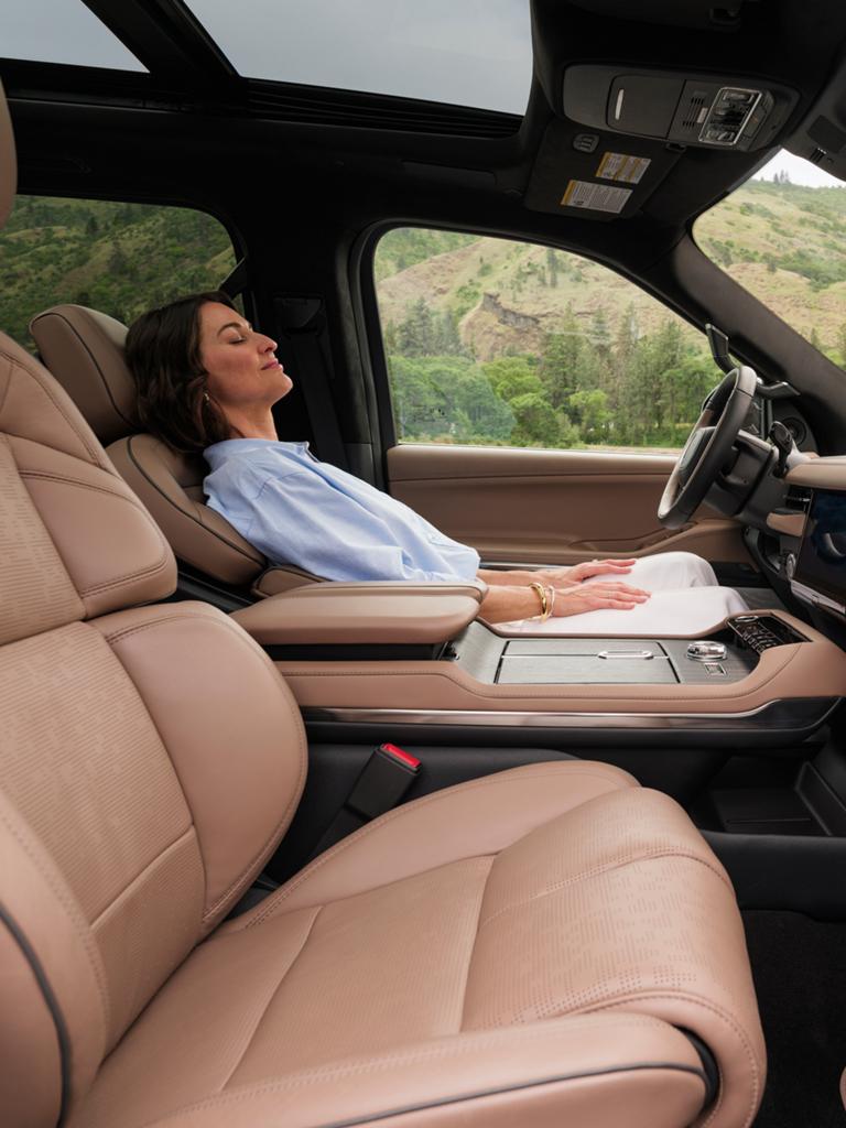 A woman reclines in a 2026 Lincoln Black Label Navigator while the Elements Rejuvenate theme is playing on-screen