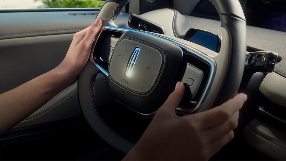 A man holding the steering wheel inside a Lincoln vehicle