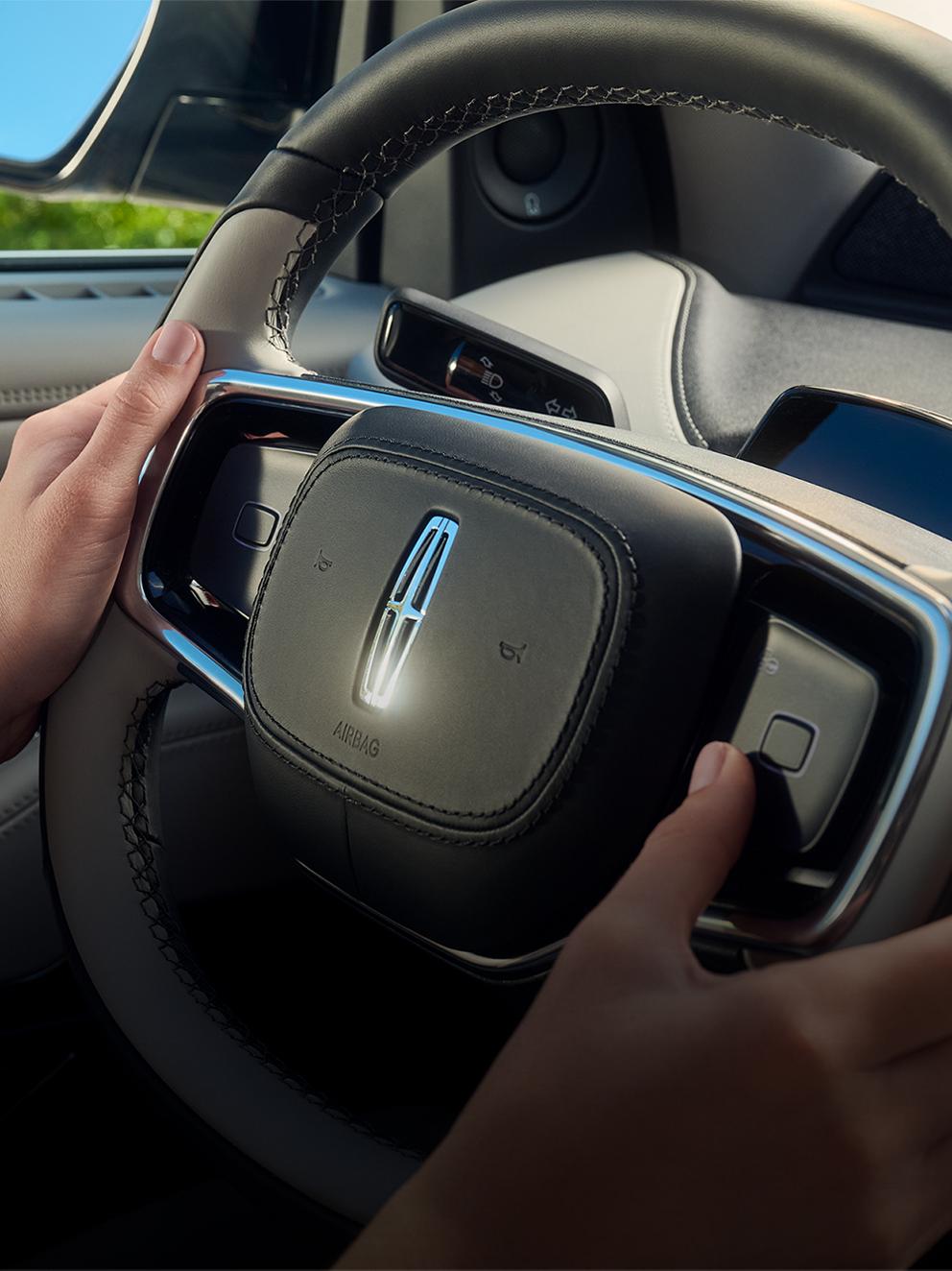 A man holding the steering wheel inside a Lincoln vehicle