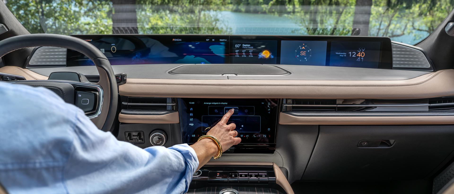 Una mujer interactuando con la pantalla táctil dentro de una Lincoln Navigator.
