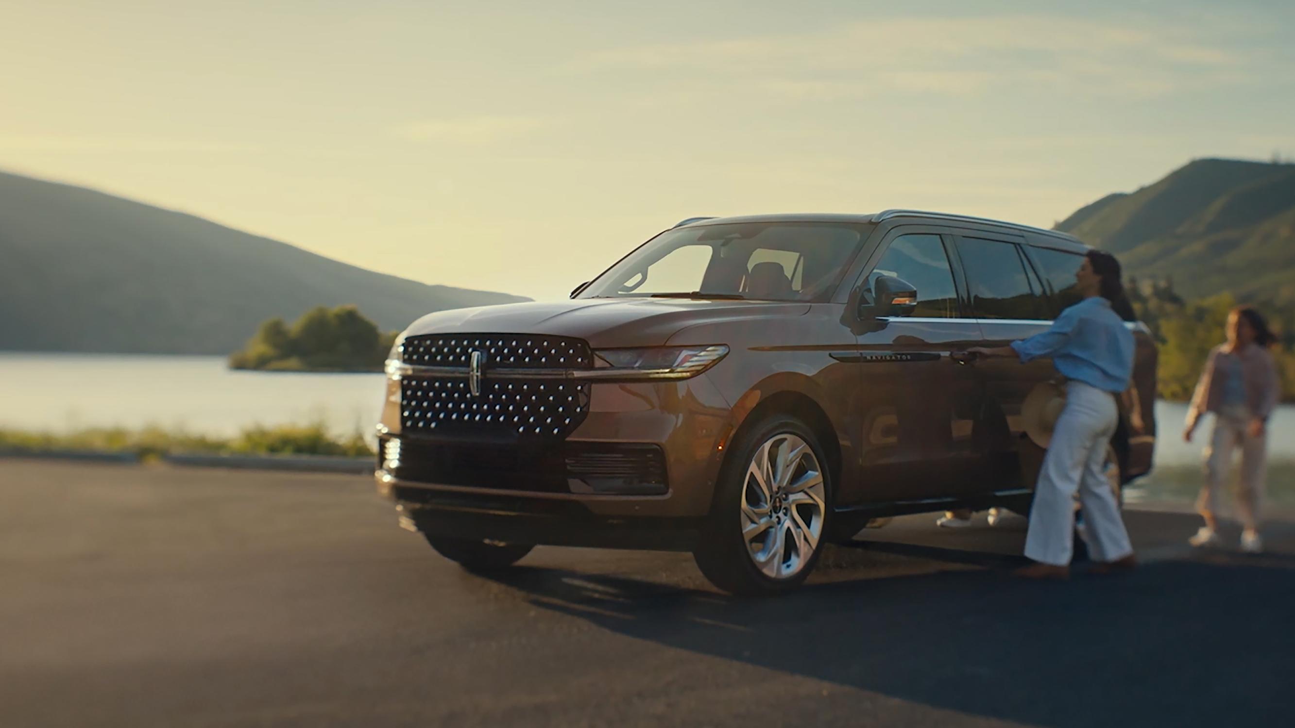 Una familia se acerca a una Lincoln Black Label Navigator 2026 y comienza la secuencia de luces Embrace