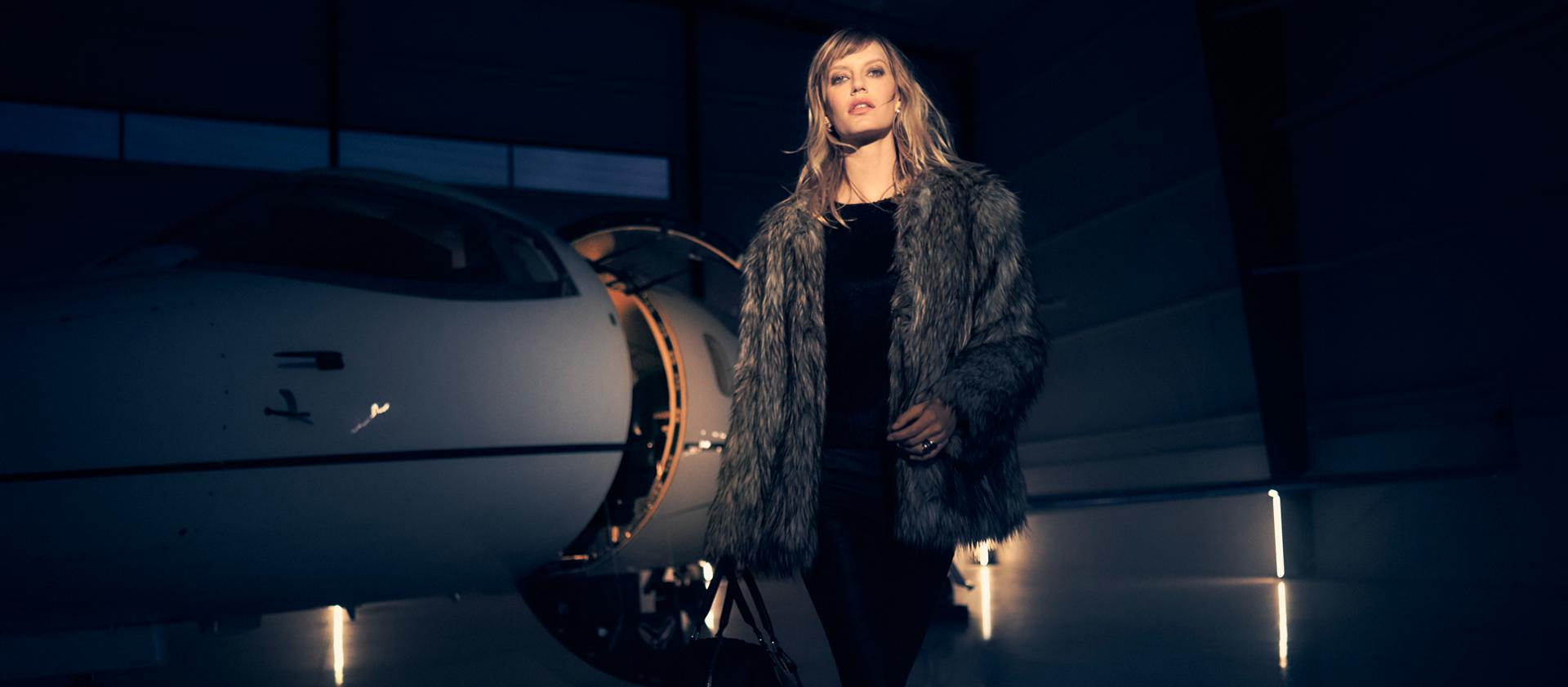 A stylishly dressed woman exits a private jet