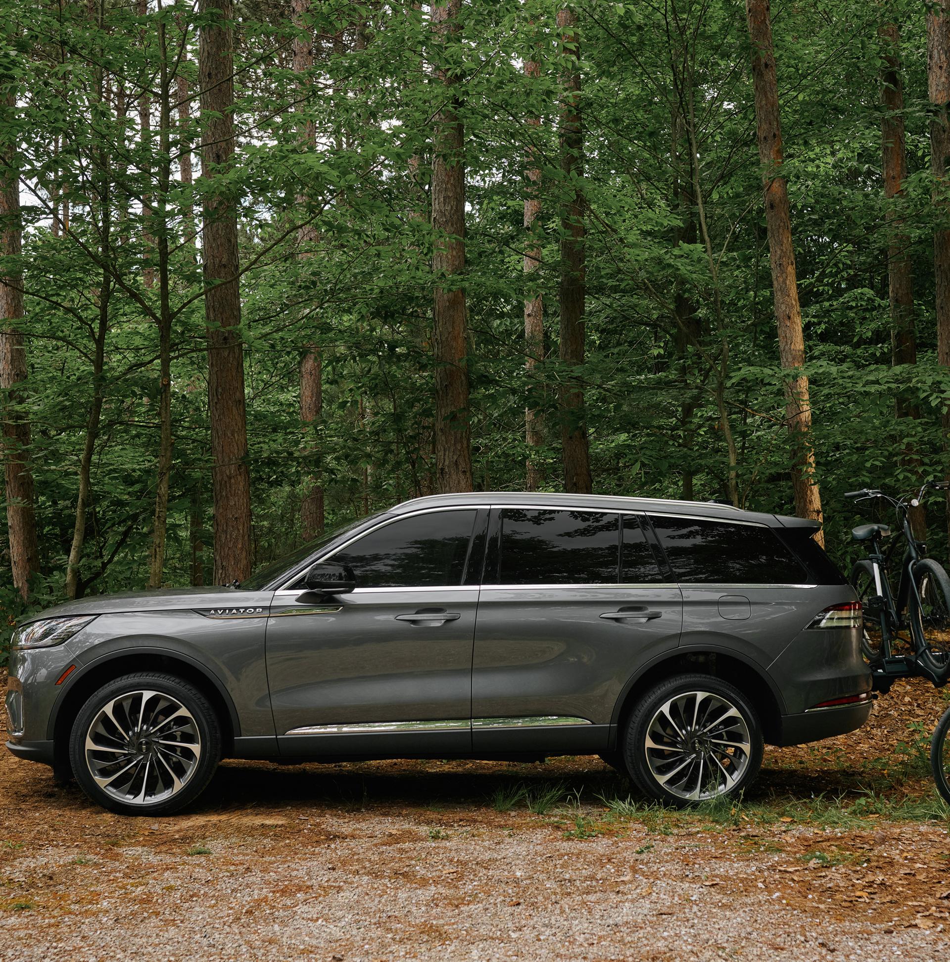 A father and son load bicycles onto a bike rack attached to a 2027 Lincoln Aviator® SUV