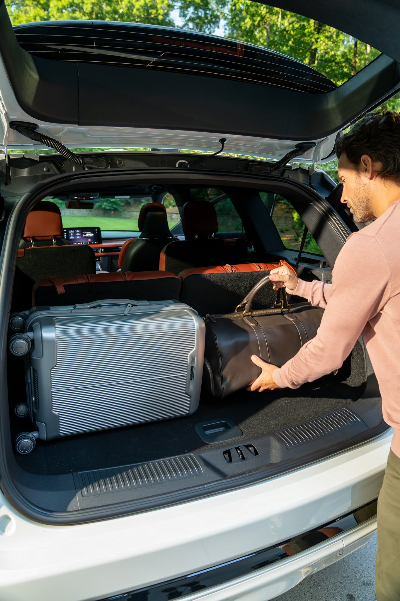 A man loads luggage into the rear of a 2025 Lincoln Aviator® SUV through the opened rear liftgate.