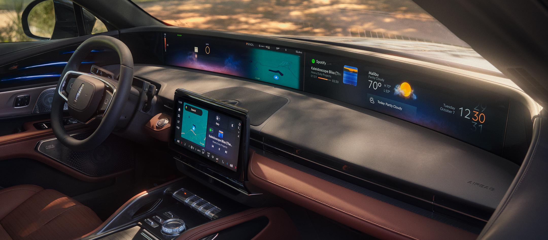 Lincoln vehicle dashboard with panoramic digital display showing maps, media, and climate controls at dusk.