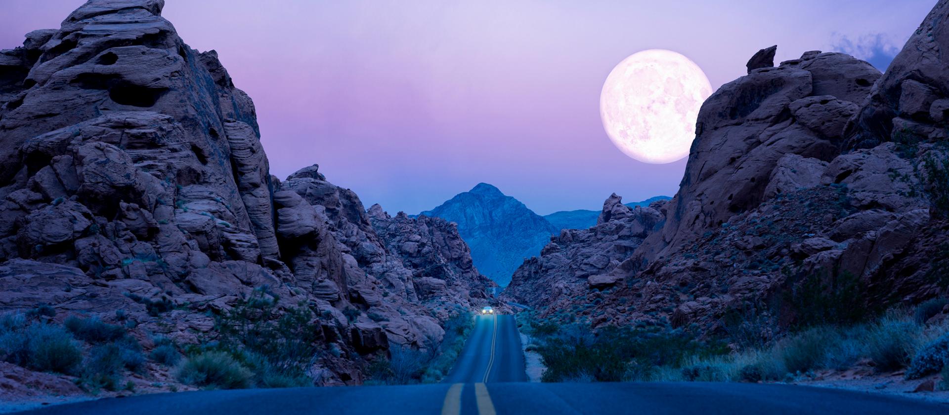 La luna cuelga baja sobre una carretera en el desierto del suroeste