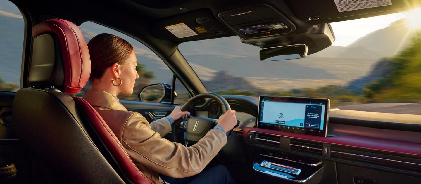A woman driving a Lincoln vehicle