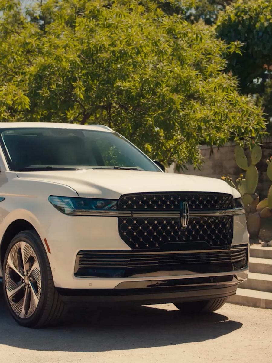 Una SUV Lincoln Navigator® 2027 está estacionada en la entrada de un refugio en el campo