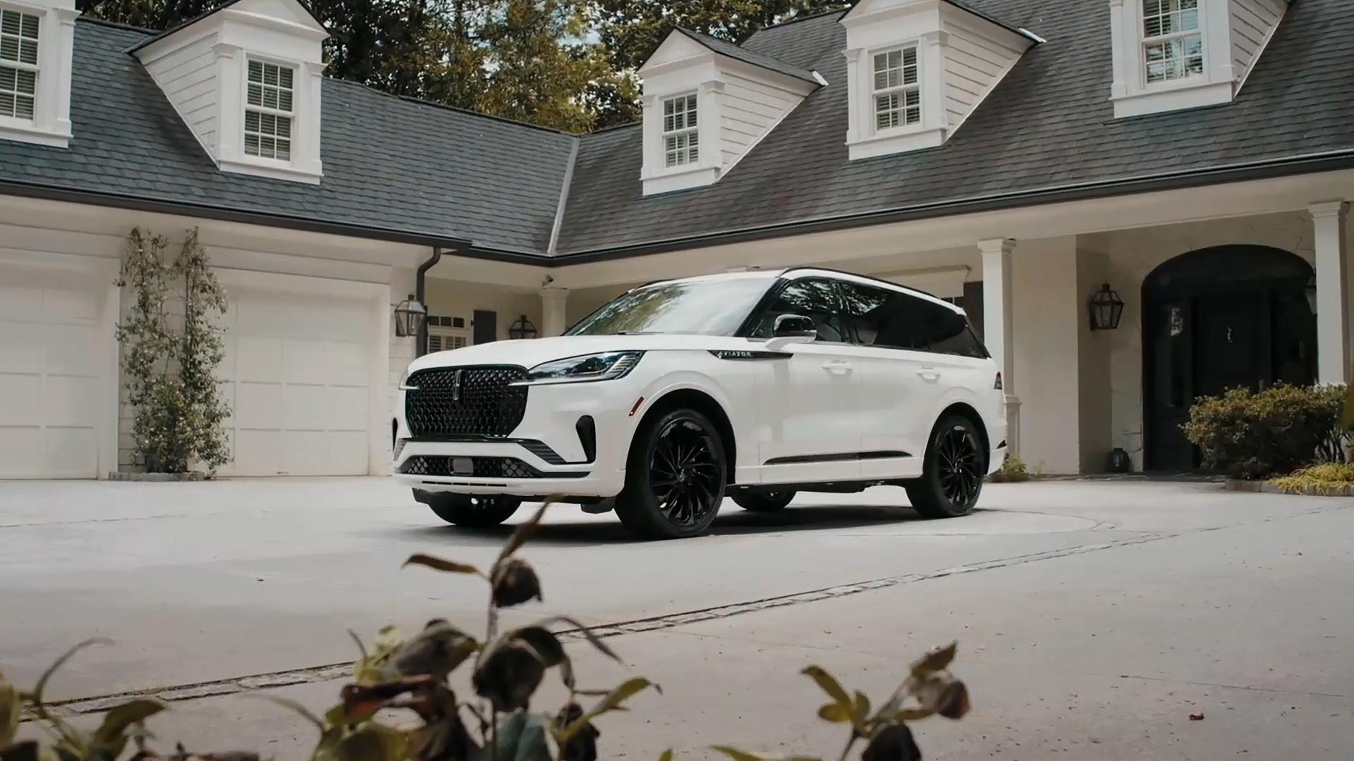 Un SUV 2026 Lincoln Aviator® está estacionado en el camino de entrada de una casa de lujo