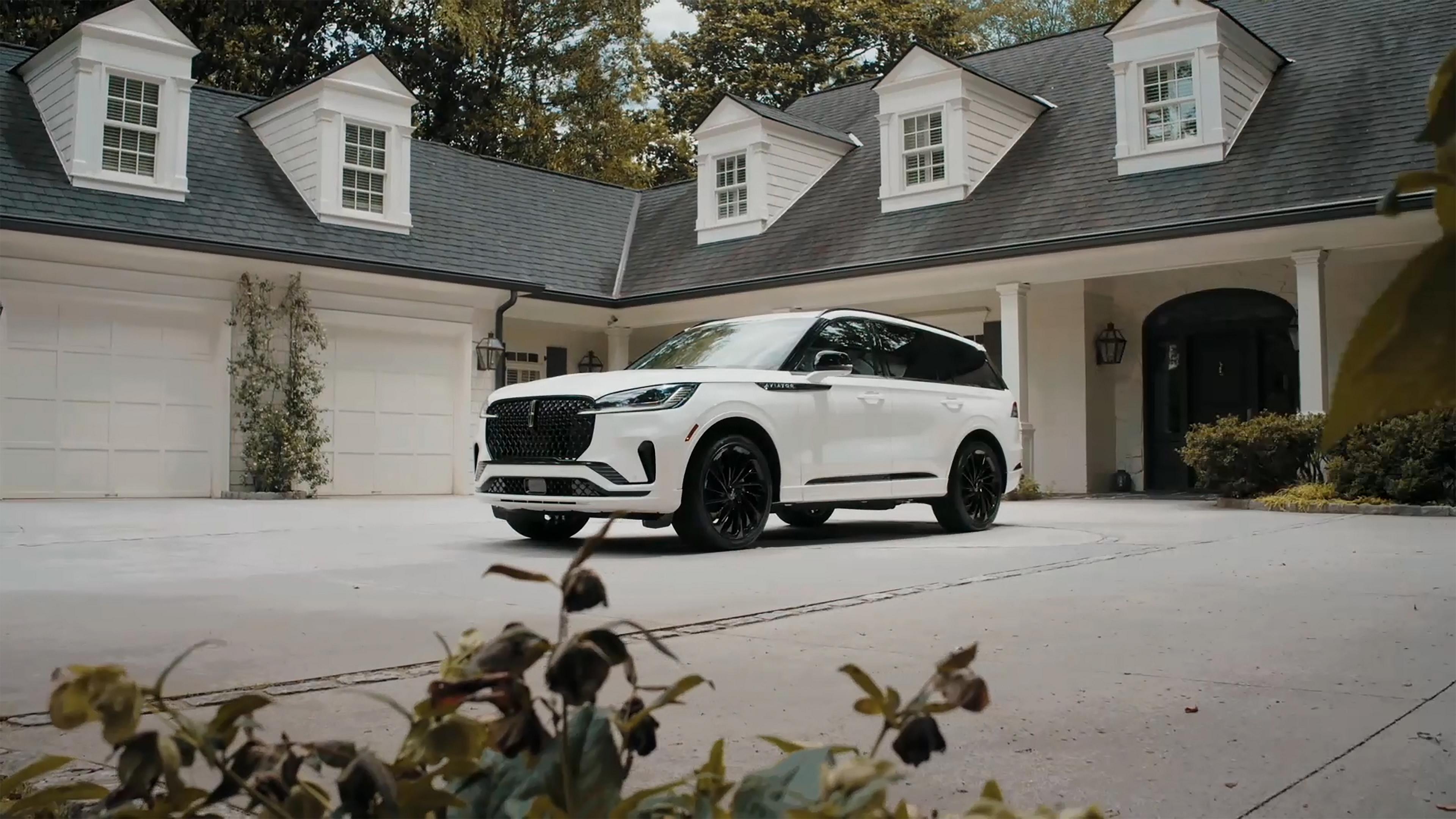 A 2026 Lincoln Aviator® SUV is parked in the driveway of a luxury home