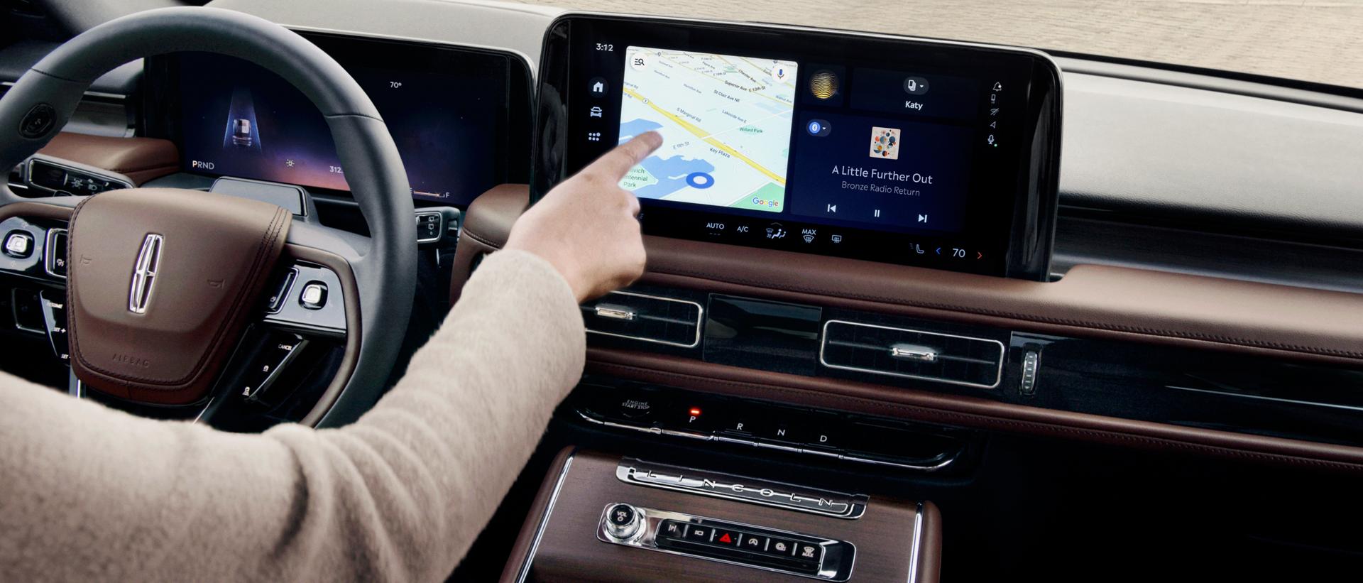 A hand reaches out to interact with the center touchscreen of a 2027 Lincoln Aviator® SUV.