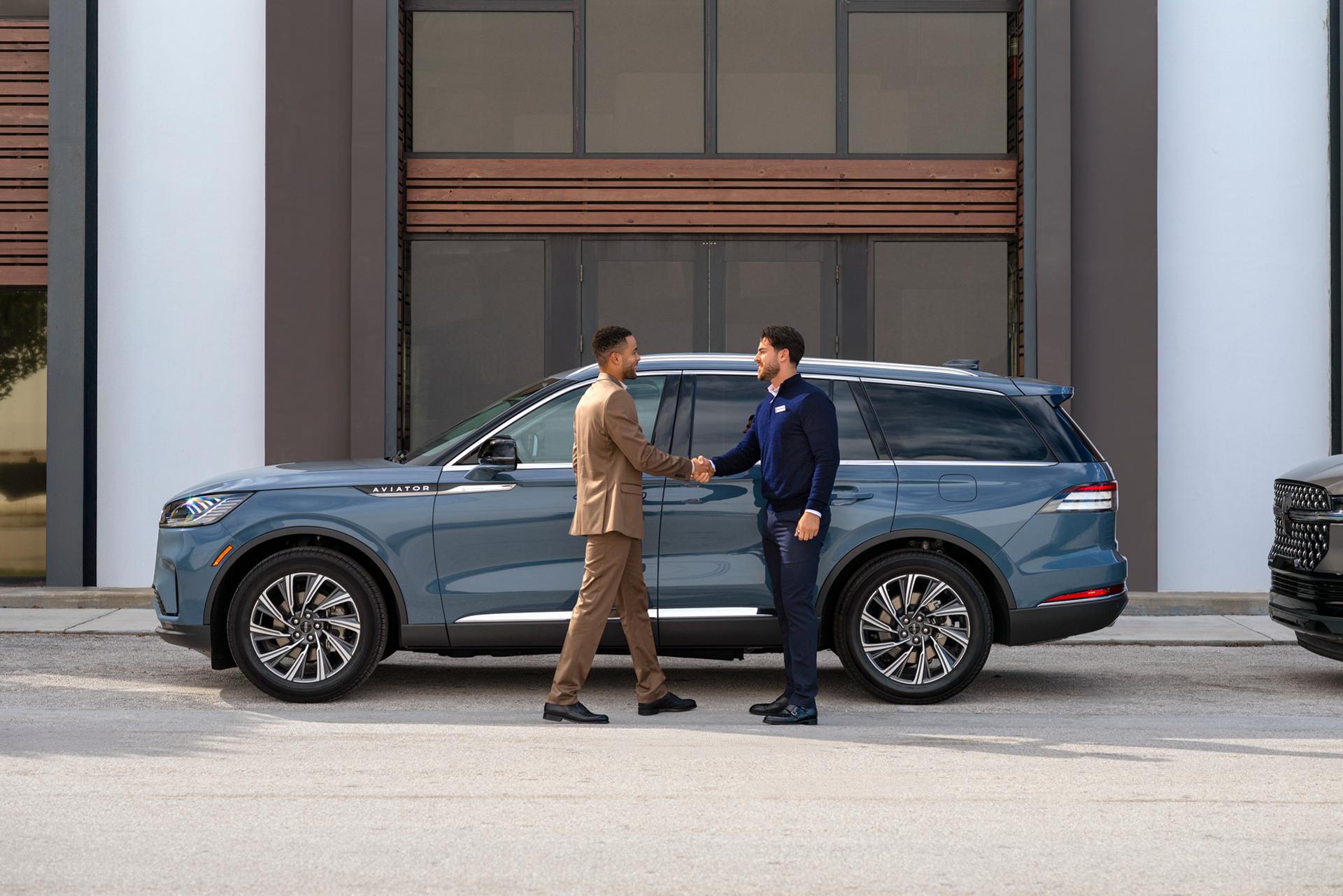 A Lincoln representative interacts with a client outside a Lincoln SUV