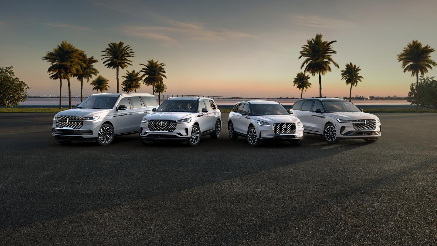 A group shot showcasing Lincoln SUVs parked in front of a body of water, with palm trees in the background.