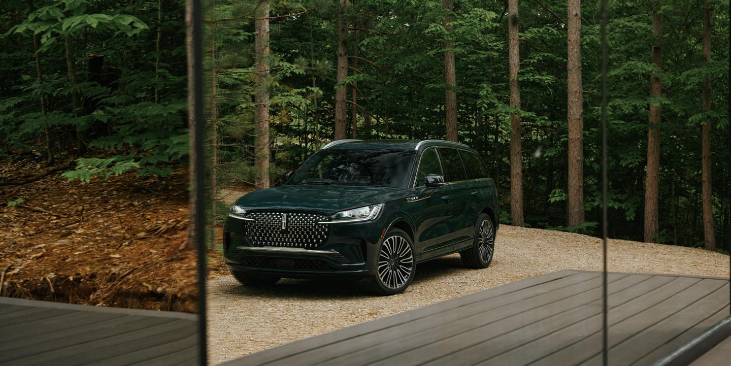 A 2027 Lincoln Aviator® Black Label™ SUV is parked in the driveway of a luxury glamping site