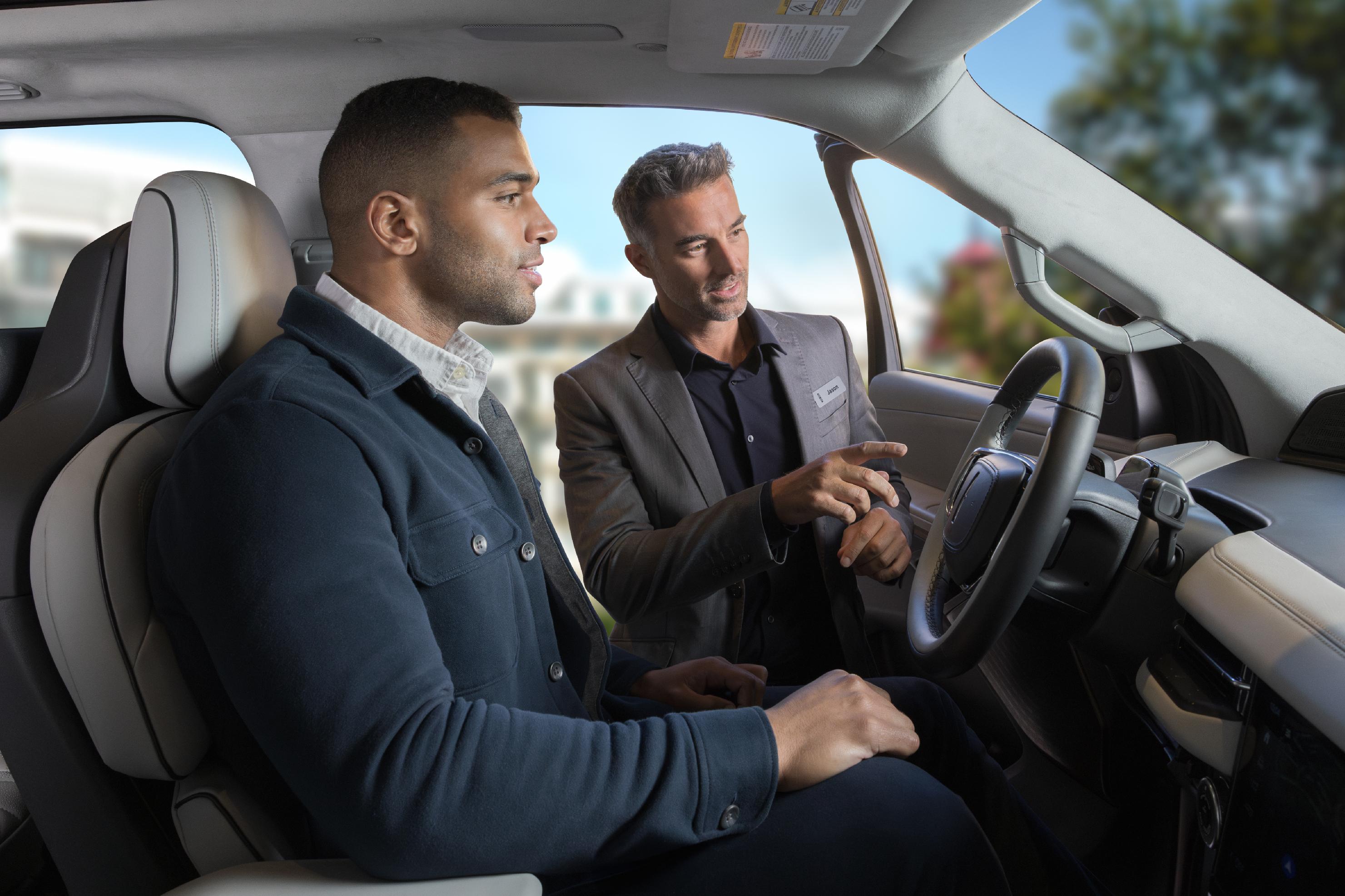 A Lincoln sales person showing a customer a feature inside the Lincoln vehicle.