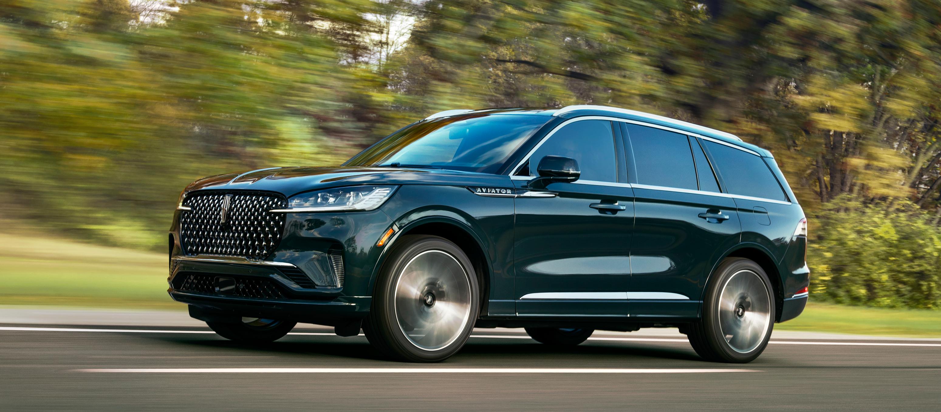 A 2026 Lincoln Aviator® SUV is shown driving on a forested road