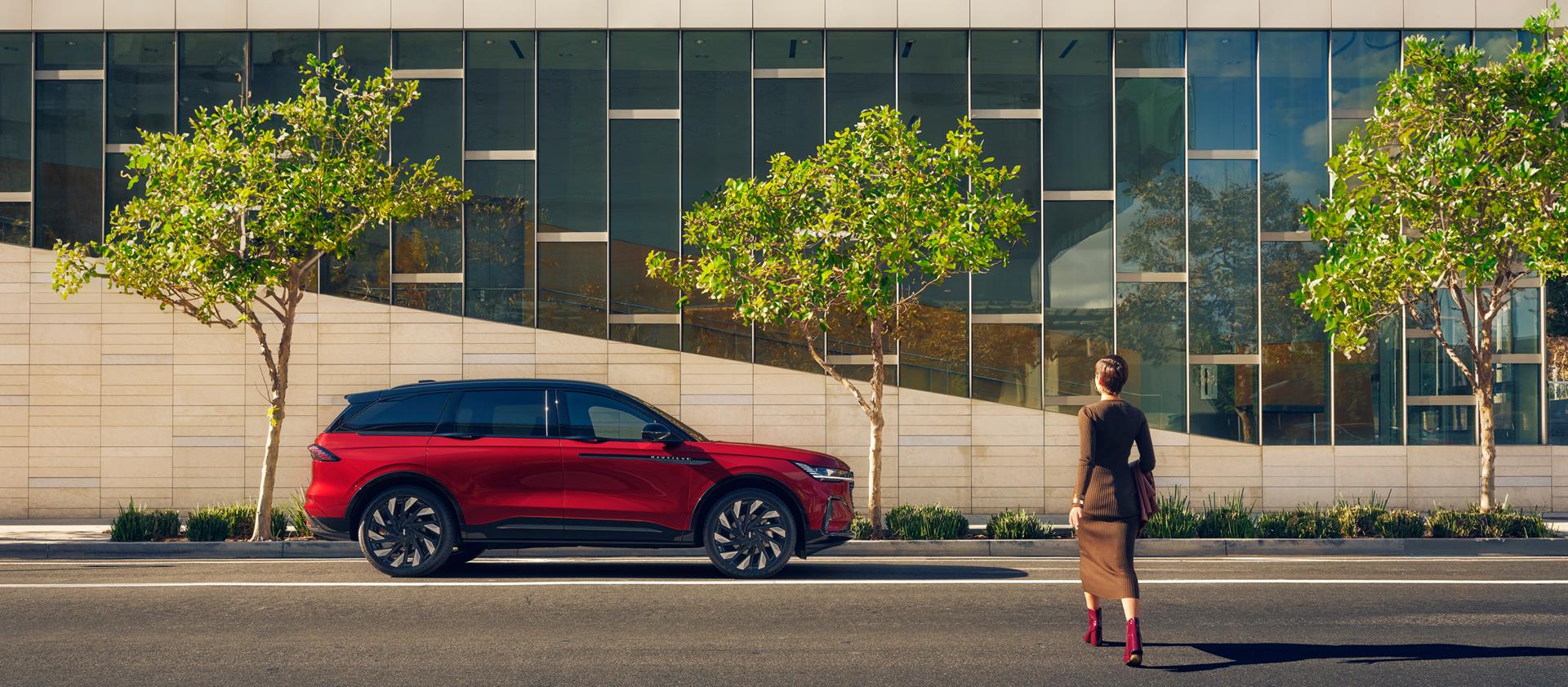 A woman crosses a city street and approaches a parked 2026 Lincoln Nautilus® SUV