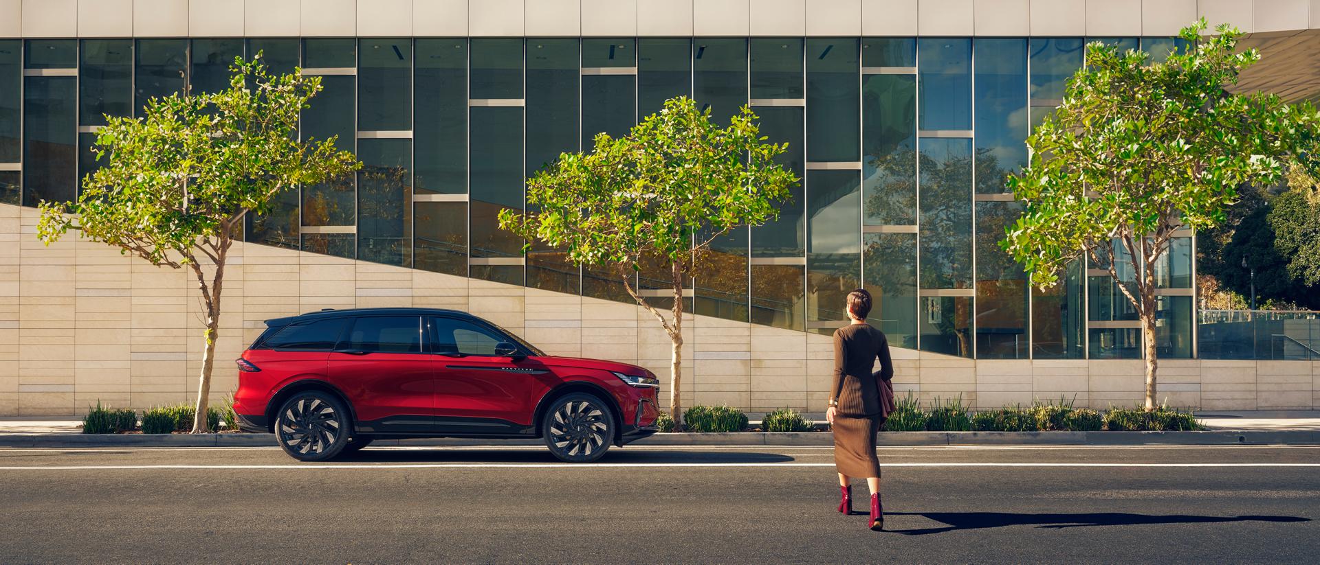 A woman crosses a city street and approaches a parked 2026 Lincoln Nautilus® SUV