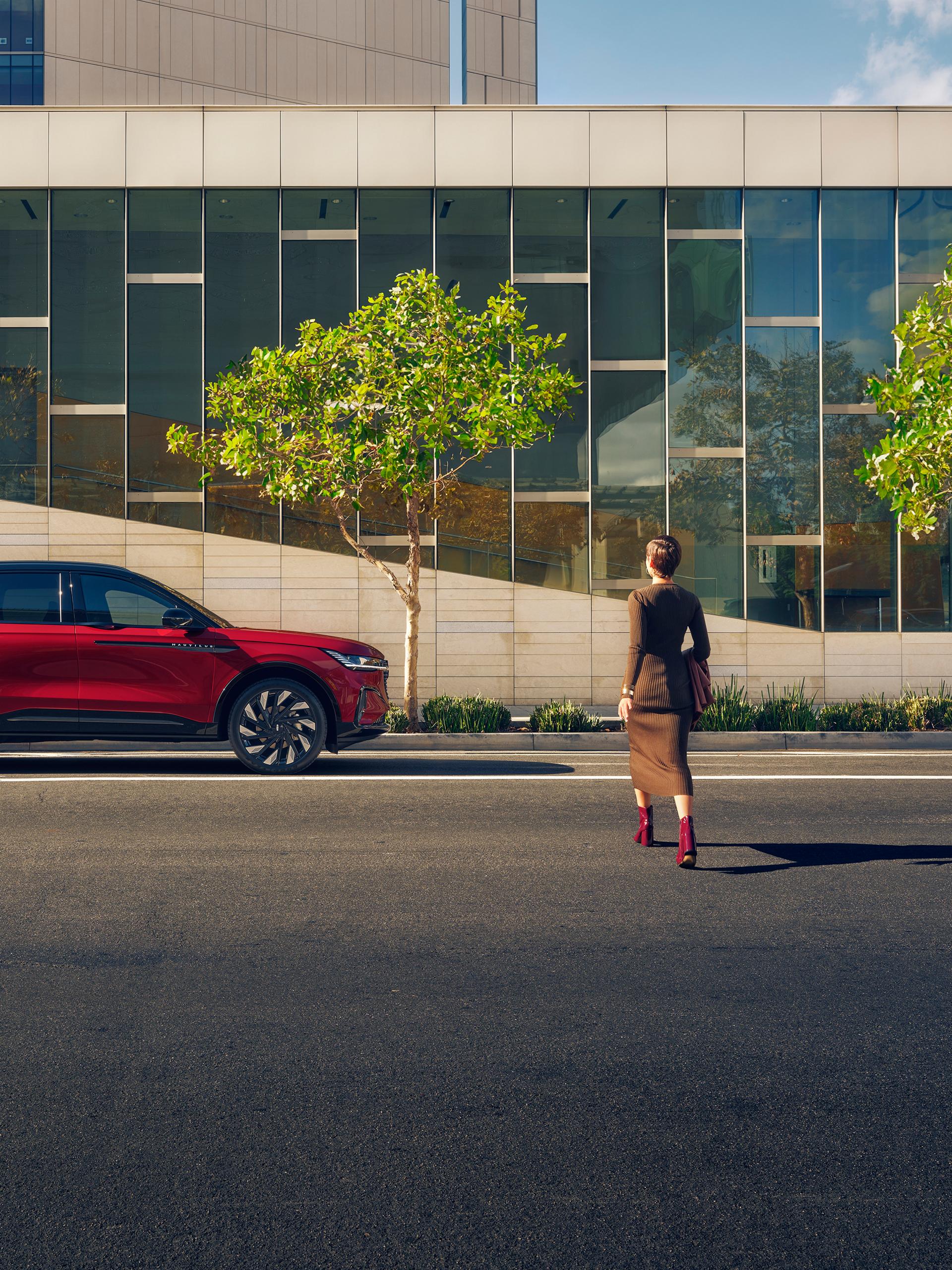A woman crosses a city street and approaches a parked 2026 Lincoln Nautilus® SUV
