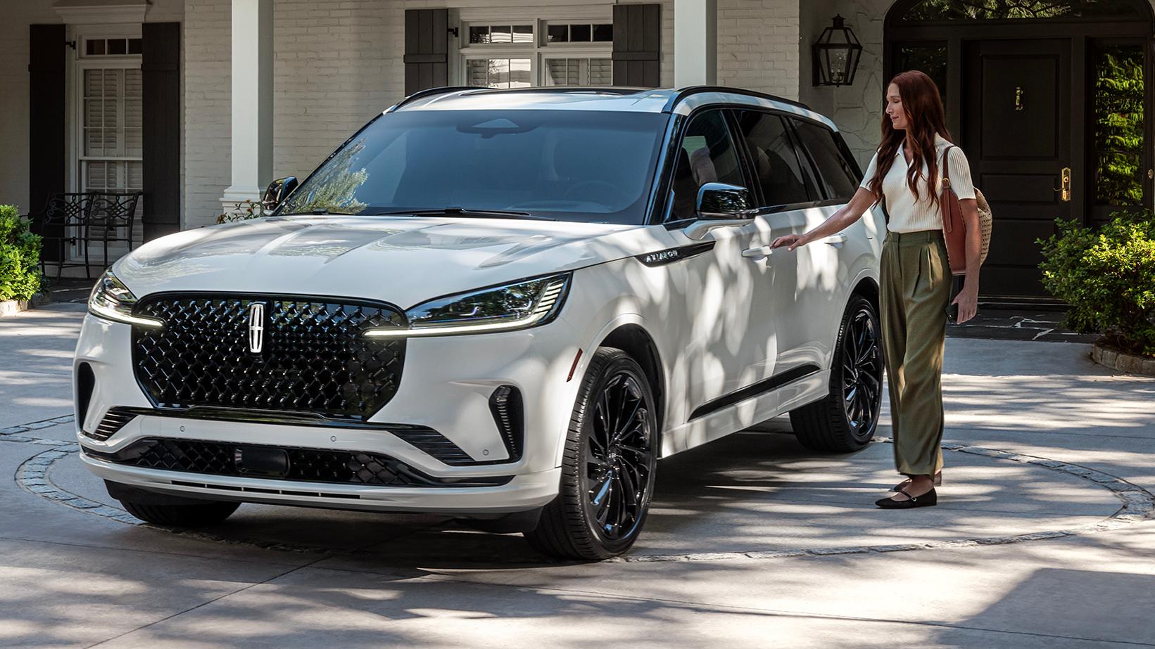 A person approaches a 2025 Lincoln Aviator® while holding a mobile phone