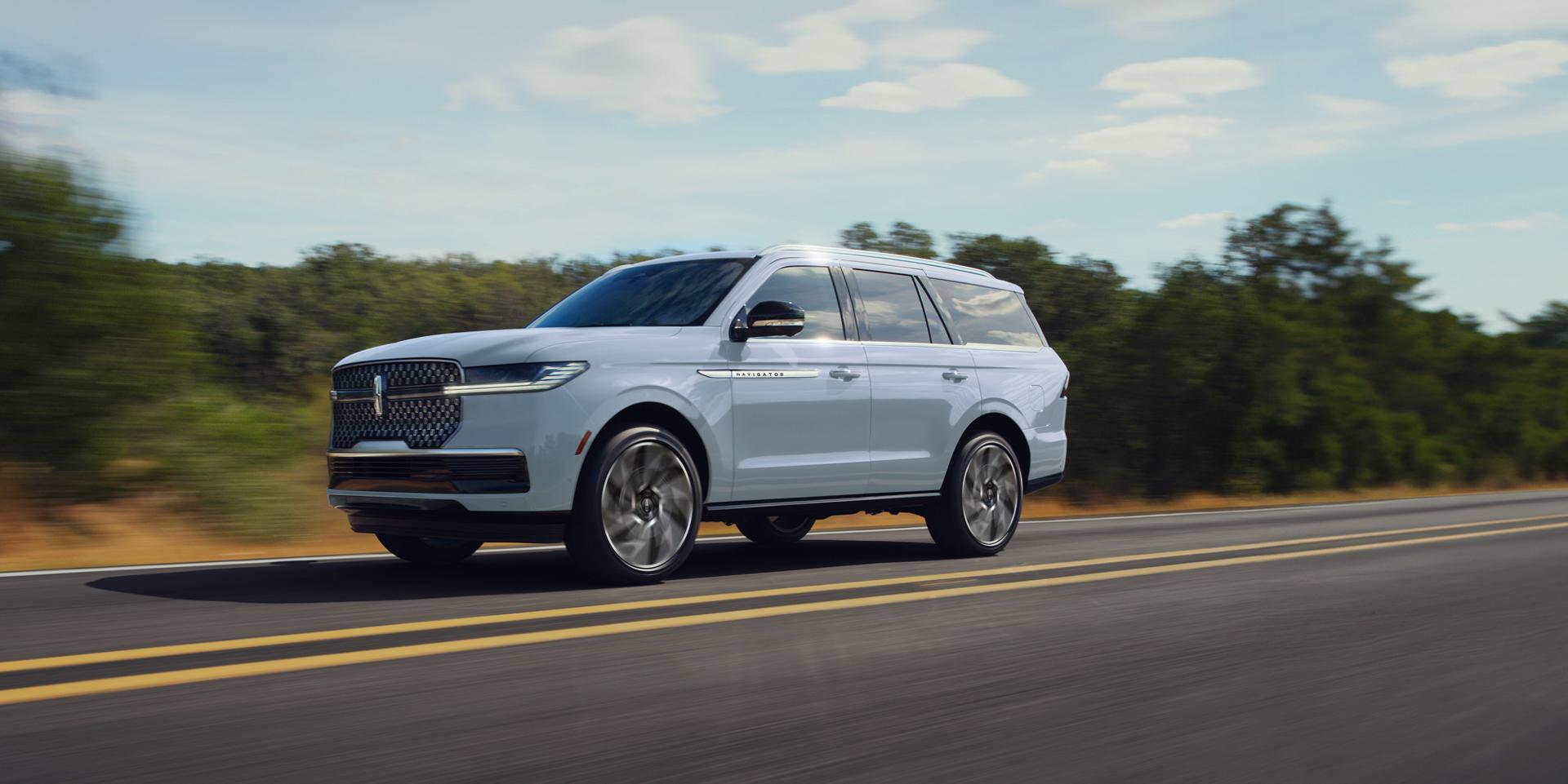 A 2027 Lincoln Navigator® Black Label™ vehicle is parked in front of a scenic waterfront with a pleasure boat hitched up